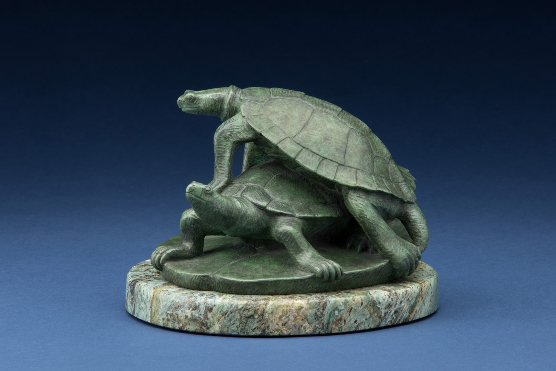 A bronze sculpture of two turtles on a marble base.