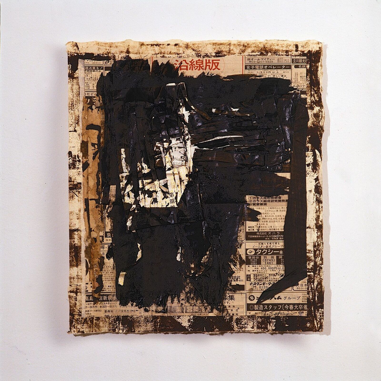 A framed mixed-media artwork featuring a dark, textured central form over a newspaper background.