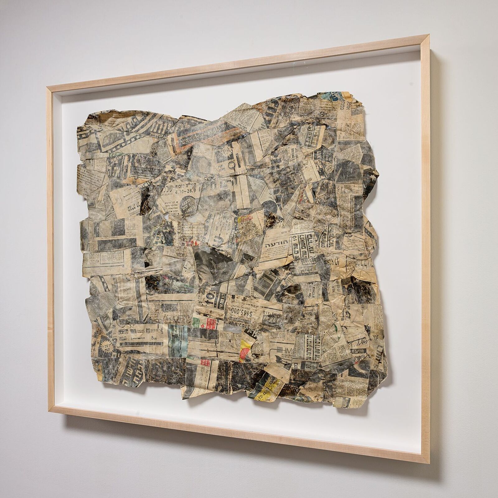 A framed collage of aged, torn paper fragments arranged in a rough square shape.