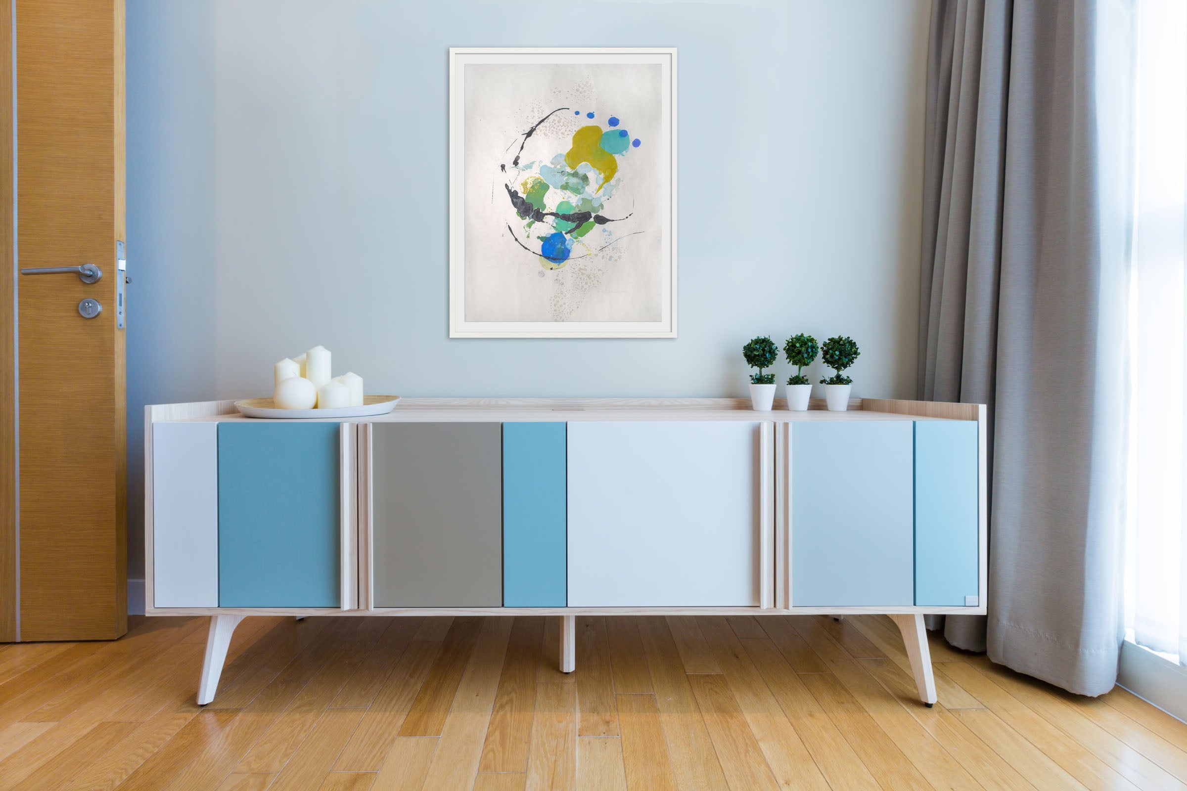A painting on a white wall with blue and yellow paint splatters.