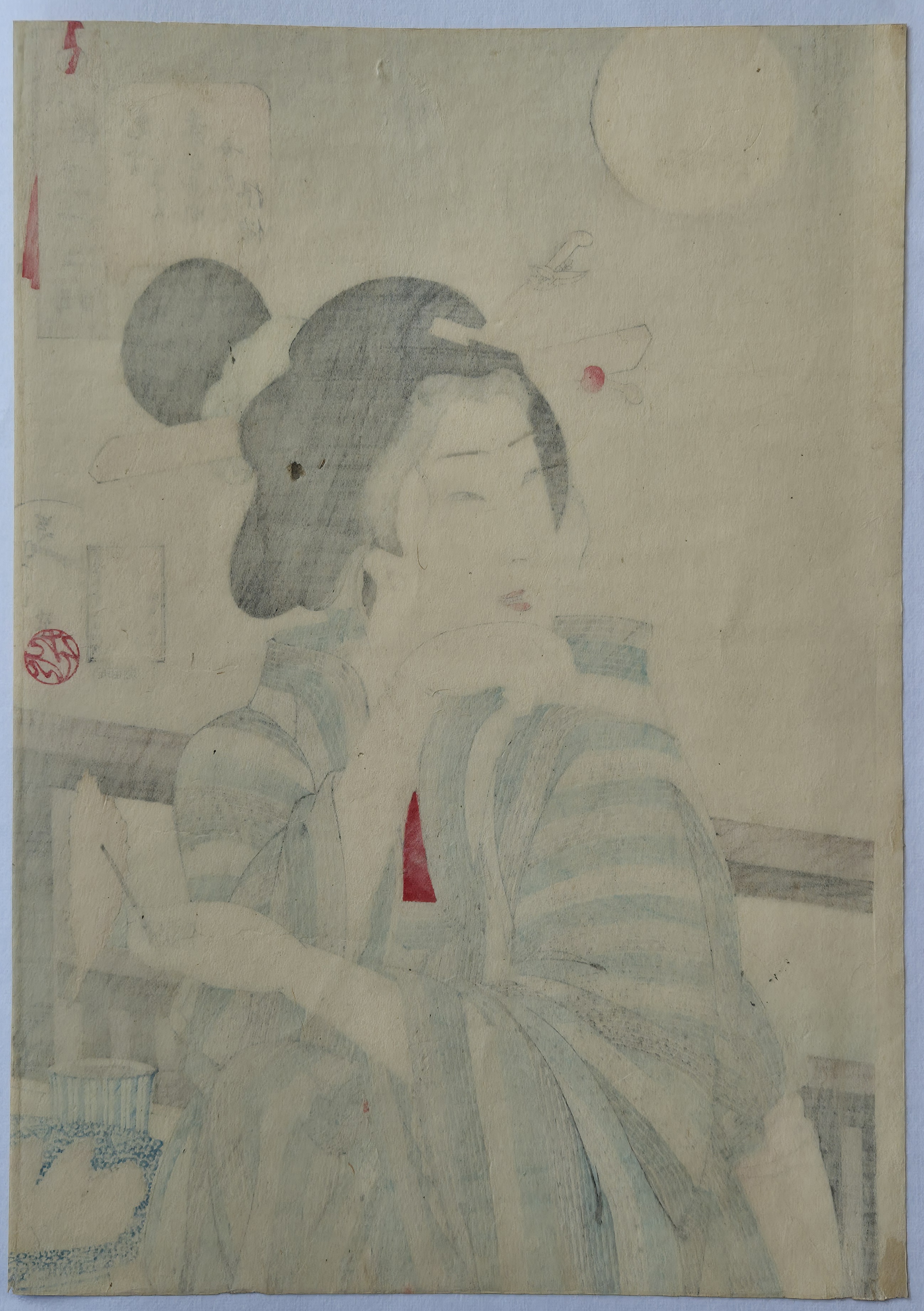 A woman in a kimono sitting at a table with chopsticks in her hair.