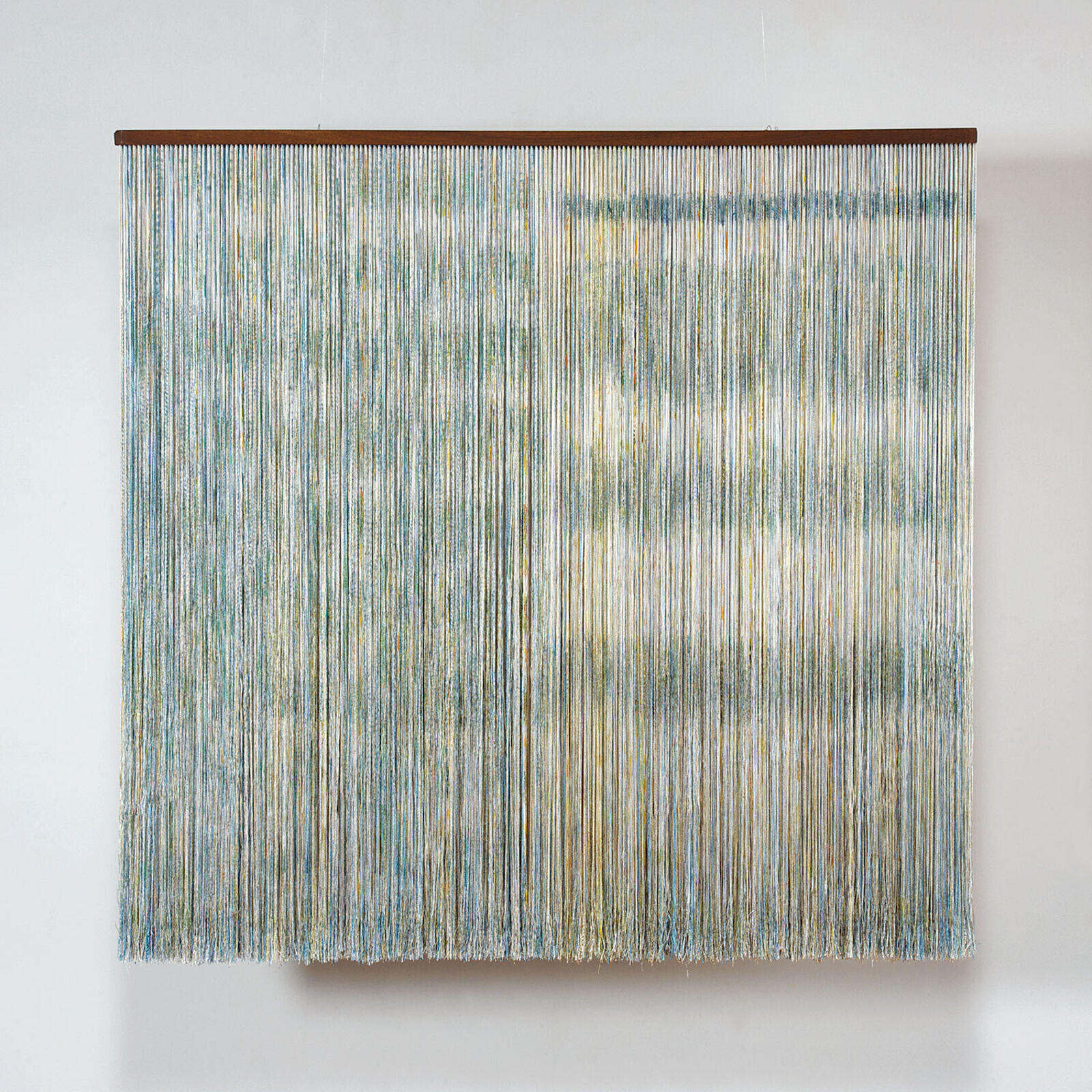 A minimalist textile artwork featuring a dense curtain of vertical threads in muted blues and creams.