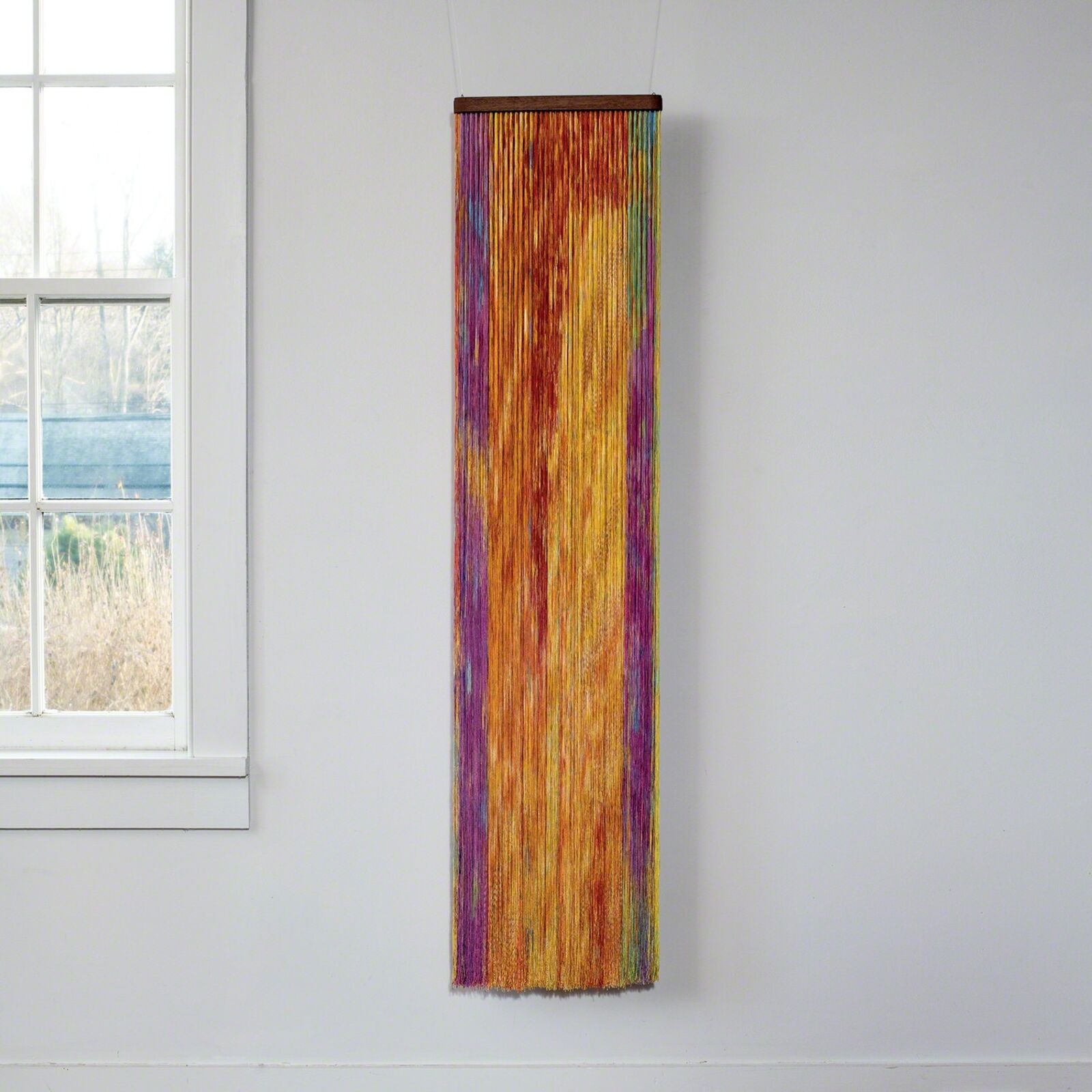 A wall hanging on a wall next to a window.