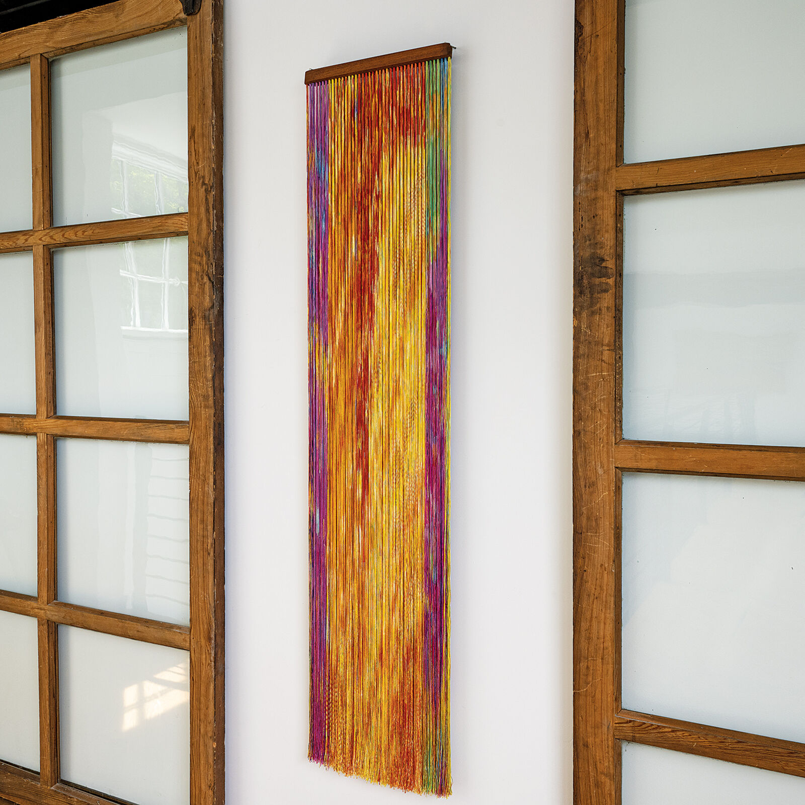 A wall hanging on a wall next to a window.