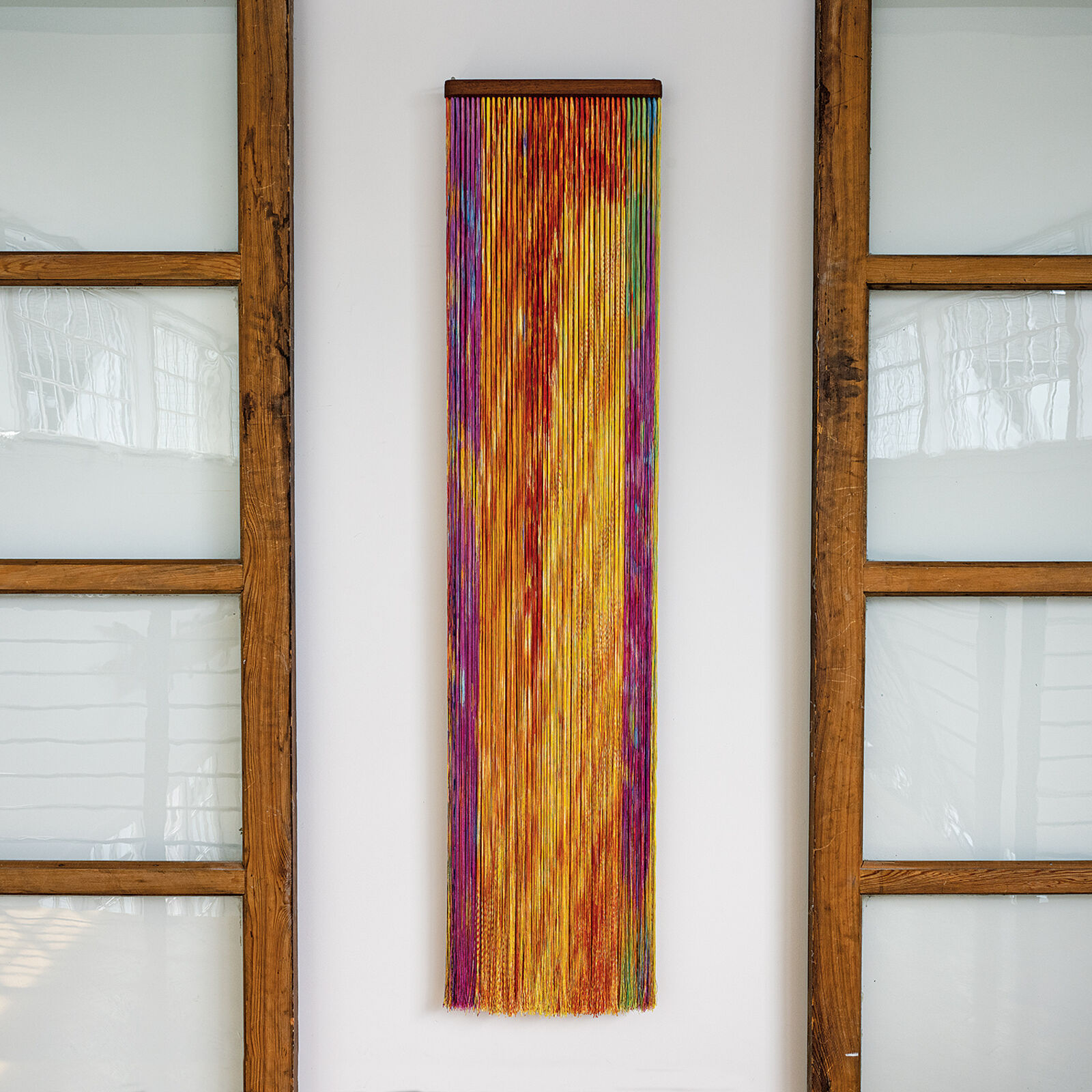 A wall hanging on a wall next to a window.