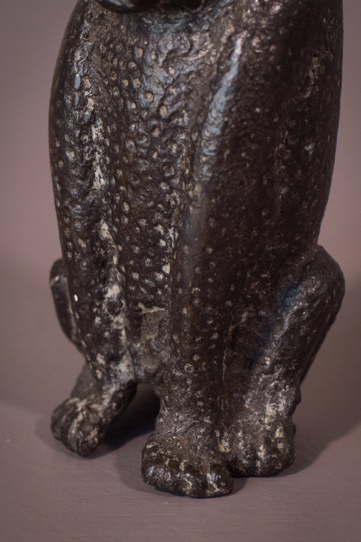 A bronze statue of a cat sitting on a table.
