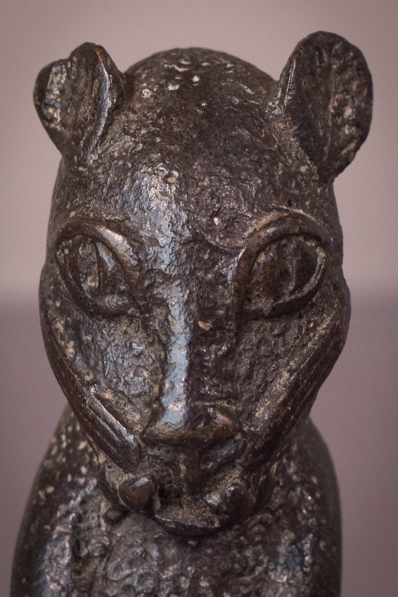 A bronze statue of a cat sitting on a table.