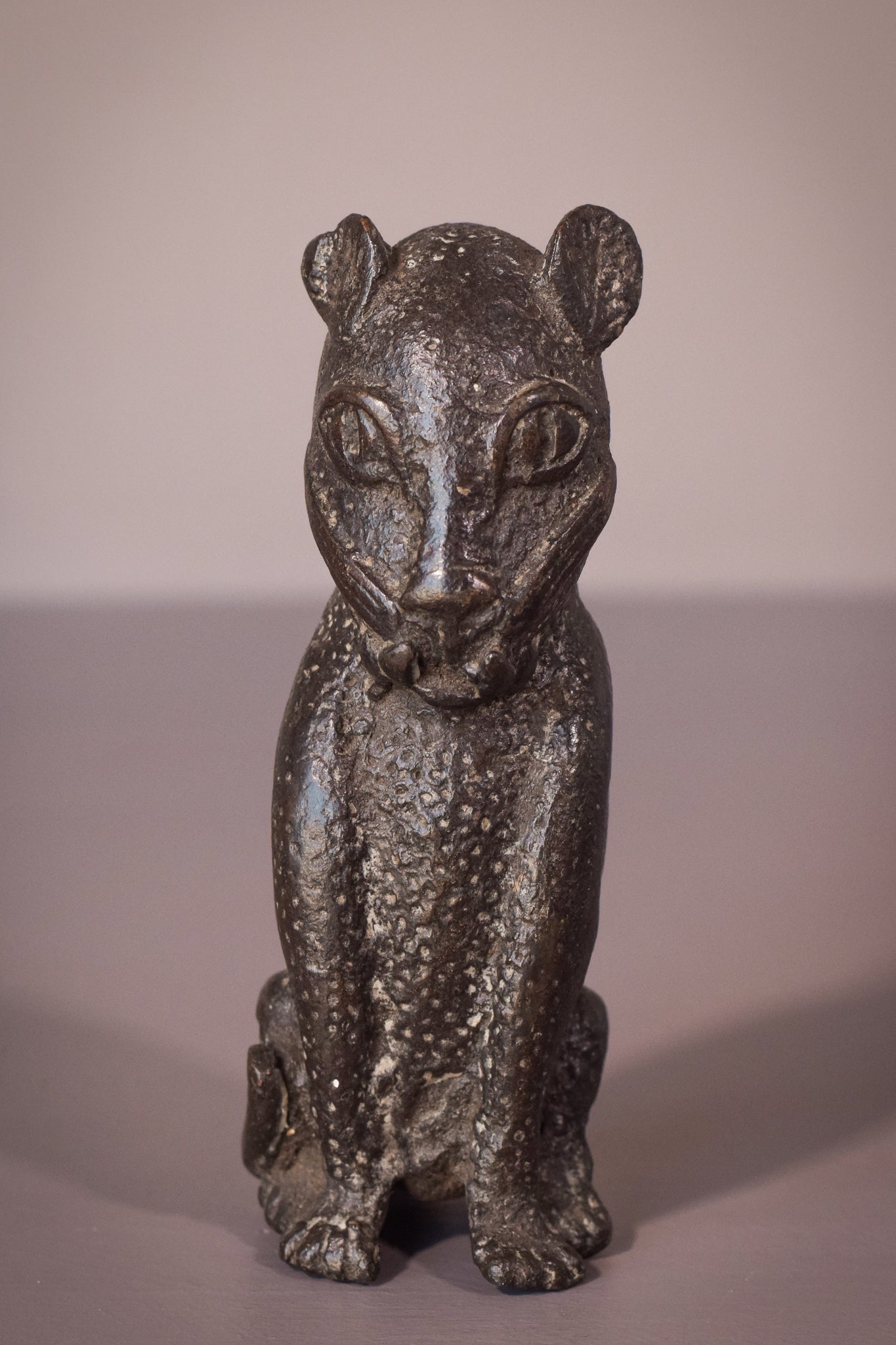 A bronze statue of a cat sitting on a table.