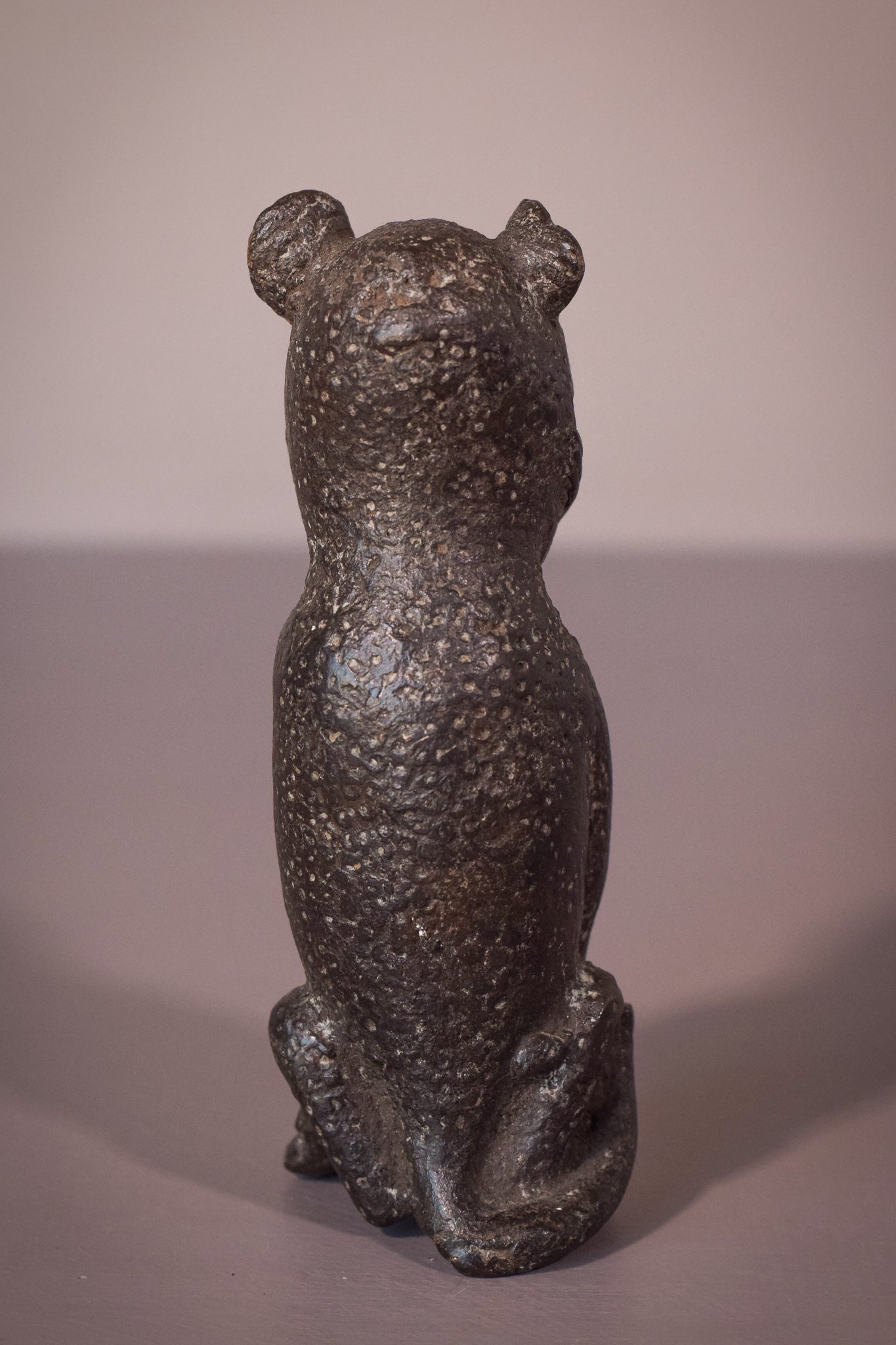A bronze statue of a cat sitting on a table.