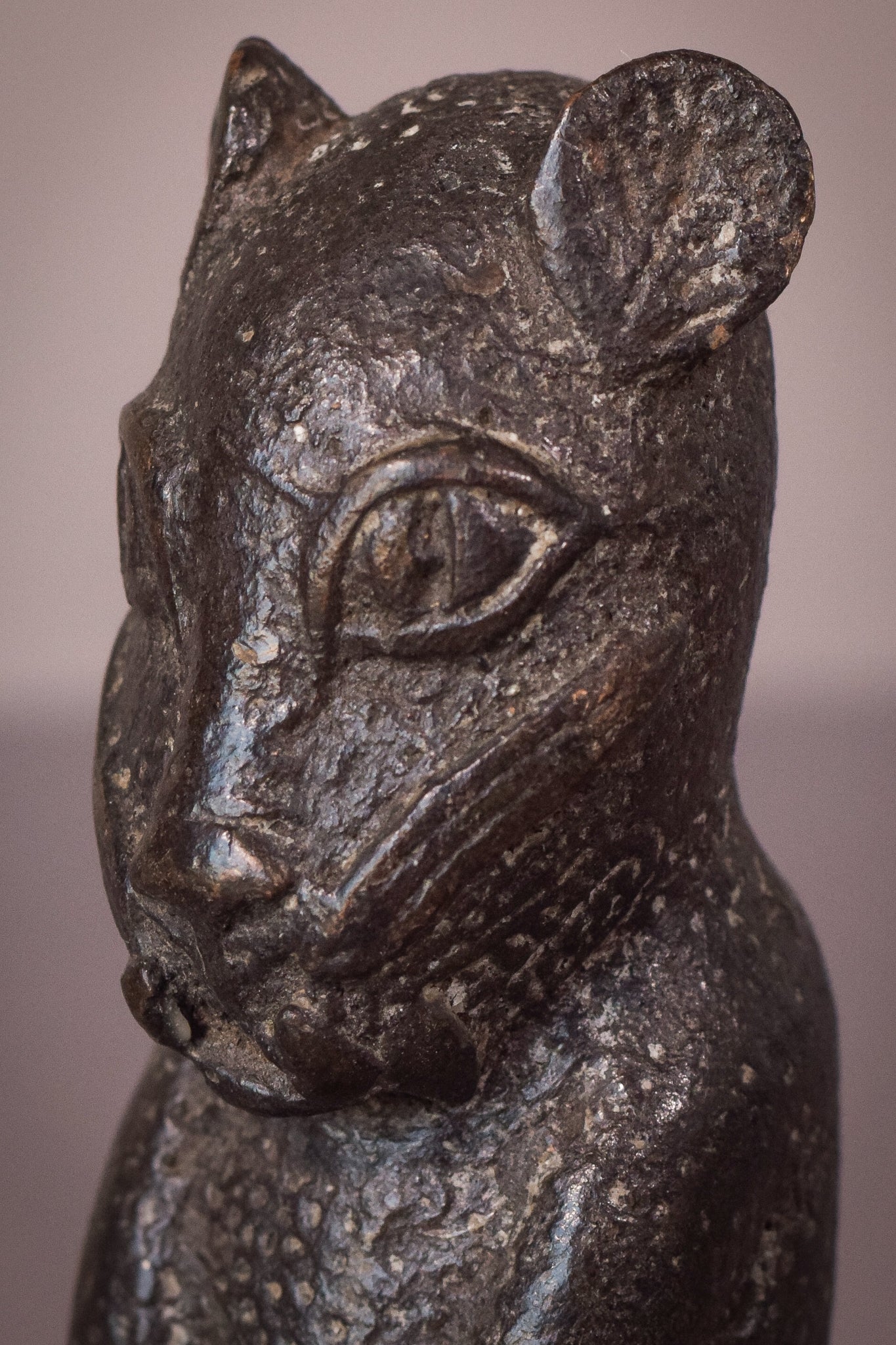 A bronze statue of a cat sitting on a table.