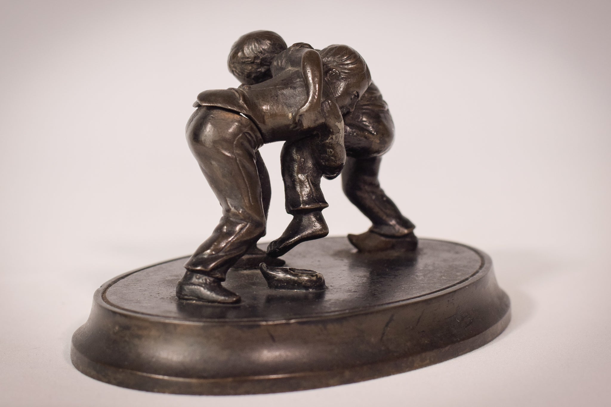 A bronze statue of two wrestlers wrestling on a metal base.