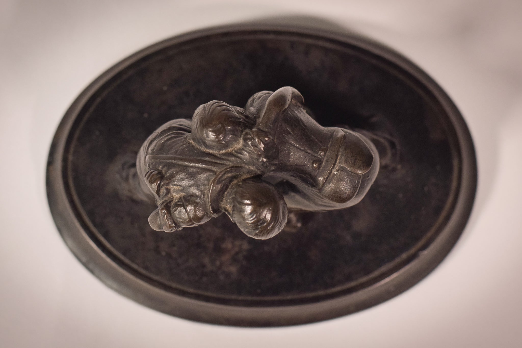 A bronze statue of two wrestlers wrestling on a metal base.