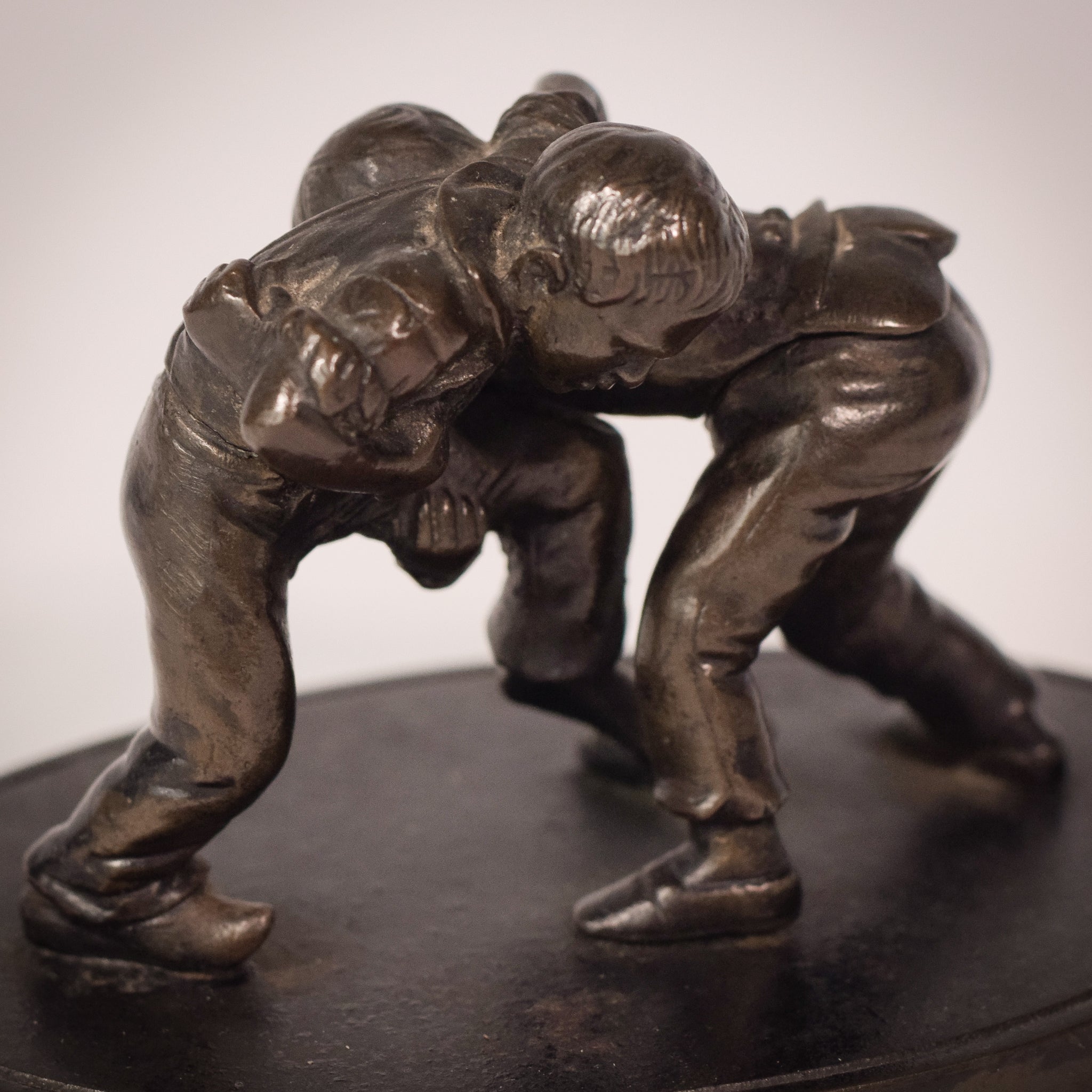 A bronze statue of two wrestlers wrestling on a metal base.