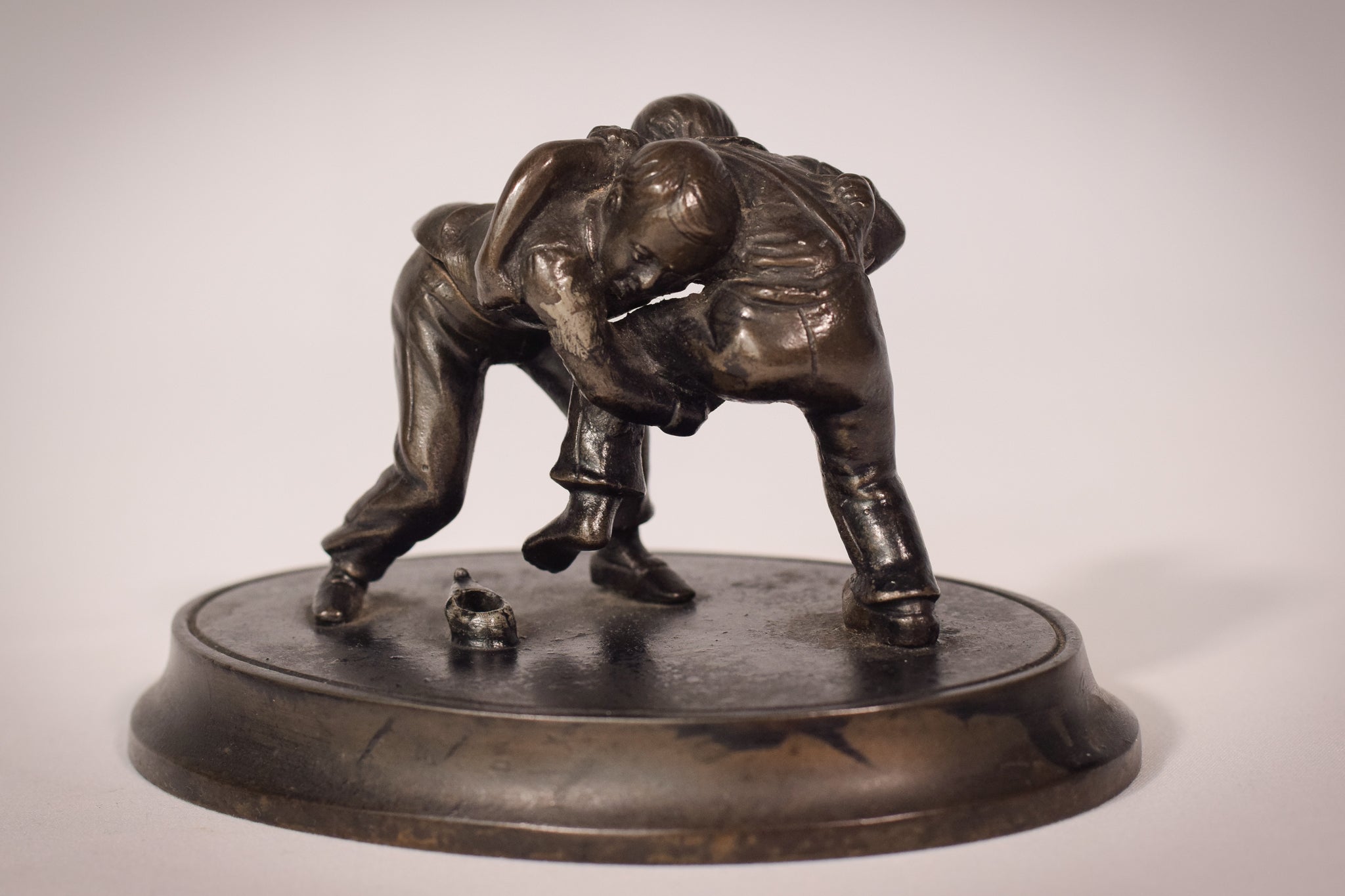 A bronze statue of two wrestlers wrestling on a metal base.