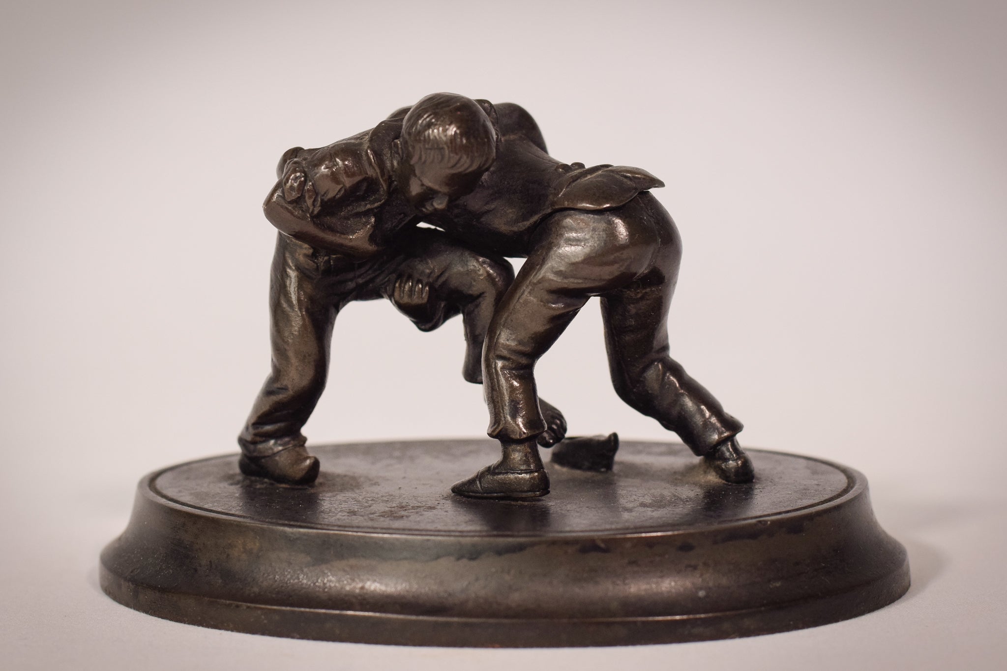 A bronze statue of two wrestlers wrestling on a metal base.