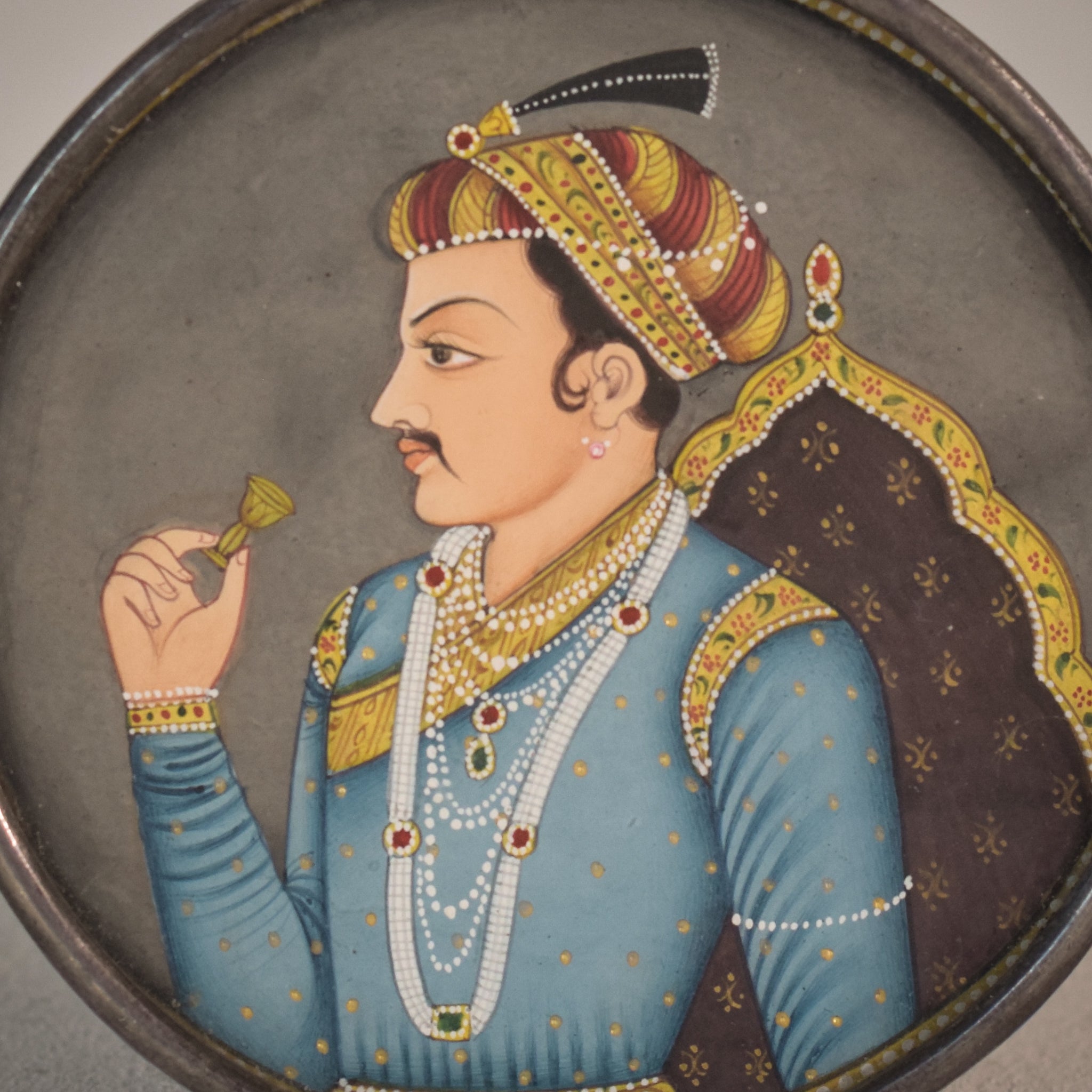 A picture of a man in a blue outfit holding a glass of wine.