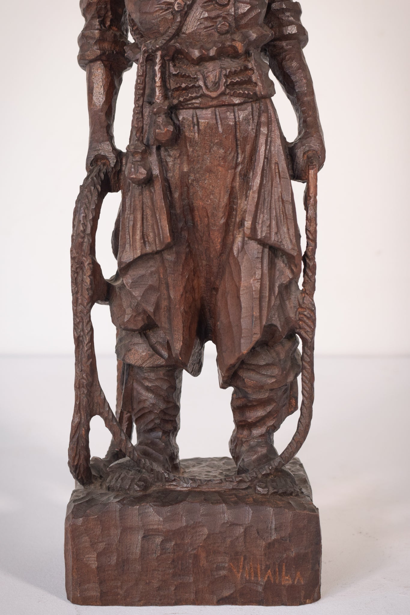 A wooden statue of a man with a cane and a hat.
