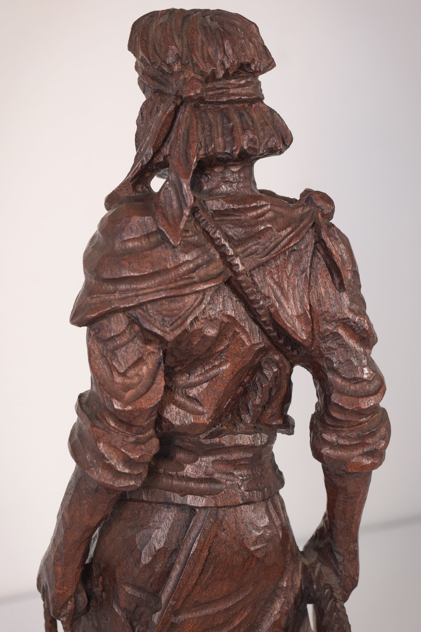 A wooden statue of a man with a cane and a hat.