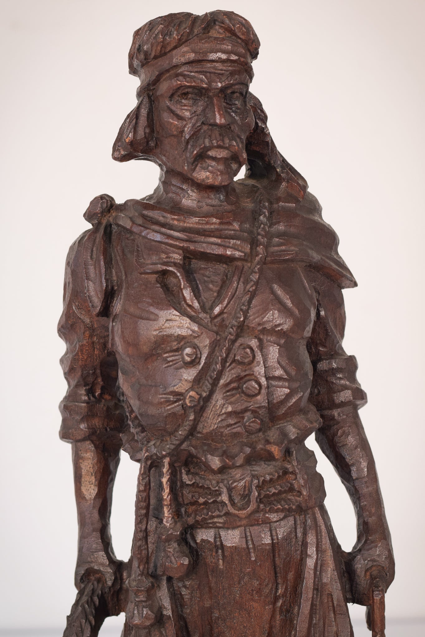 A wooden statue of a man with a cane and a hat.