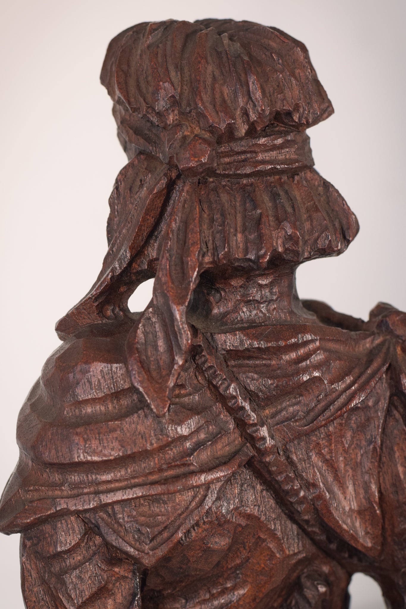 A wooden statue of a man with a cane and a hat.