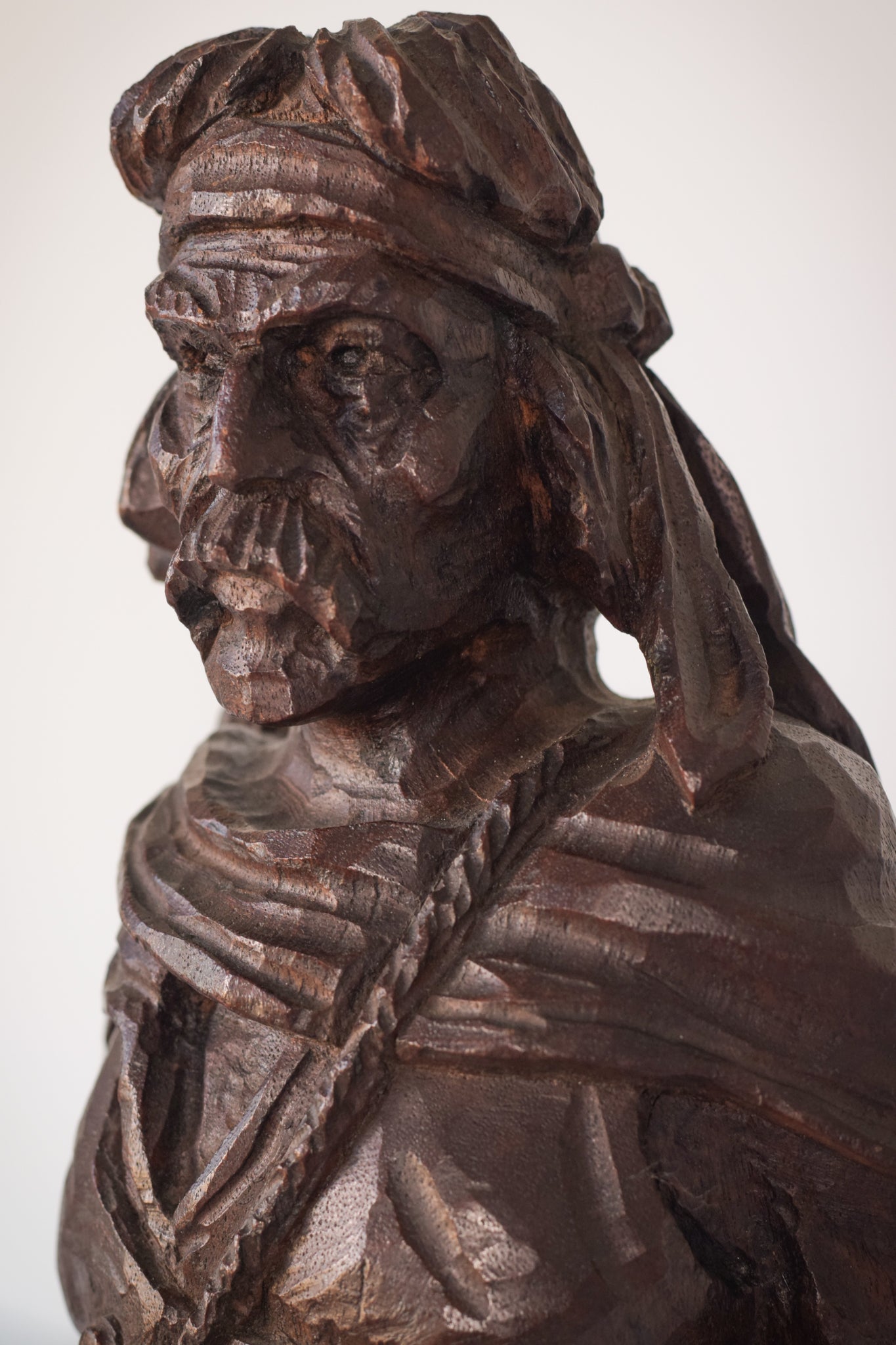 A wooden statue of a man with a cane and a hat.