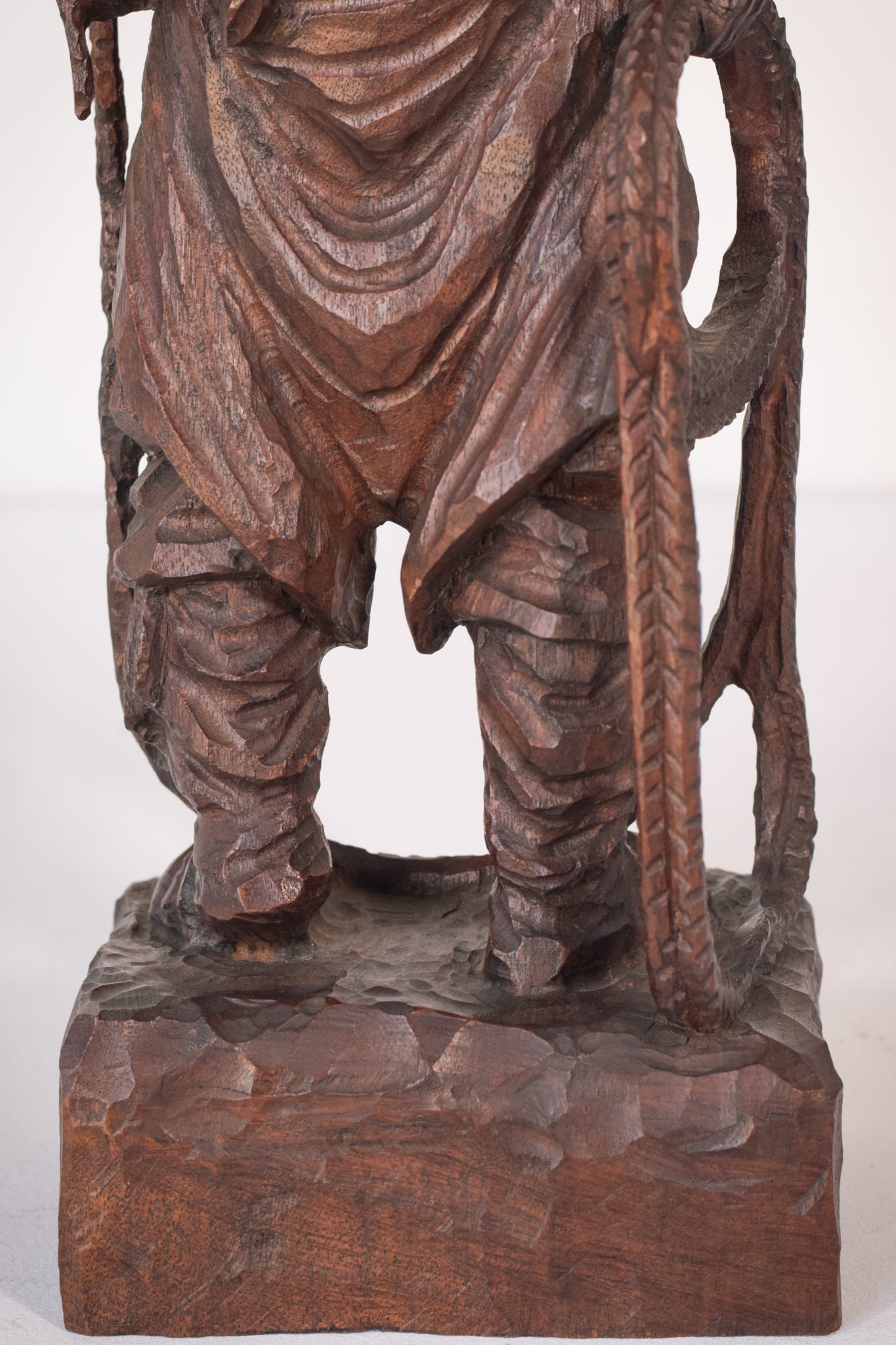 A wooden statue of a man with a cane and a hat.