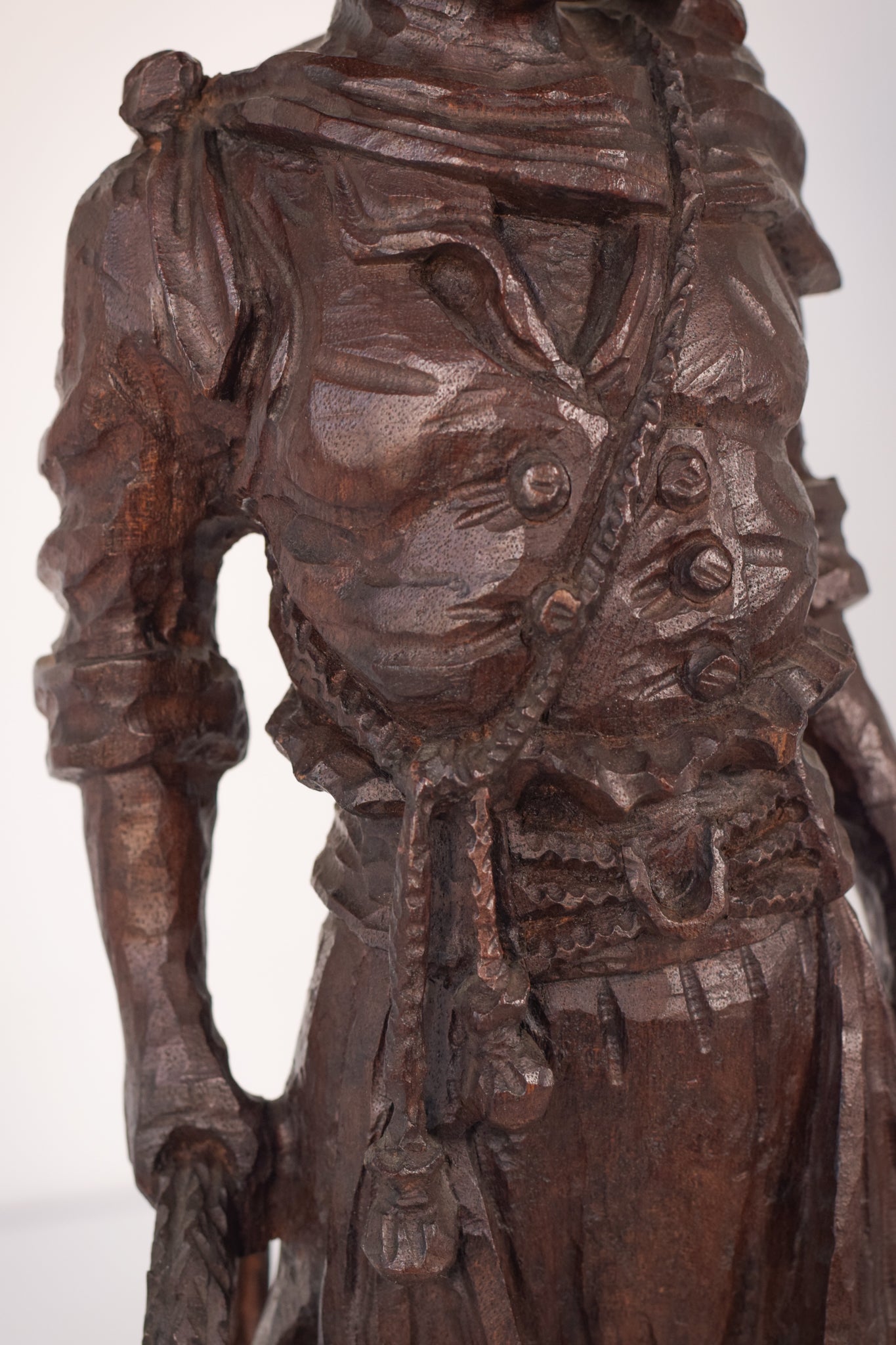 A wooden statue of a man with a cane and a hat.
