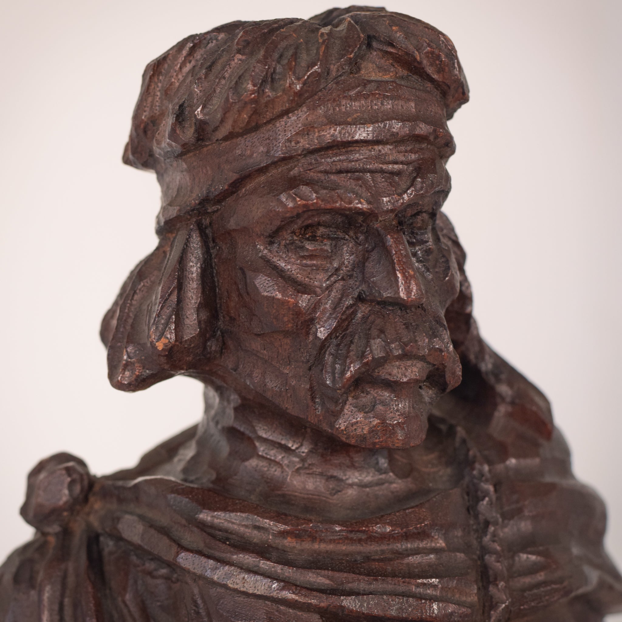 A wooden statue of a man with a cane and a hat.