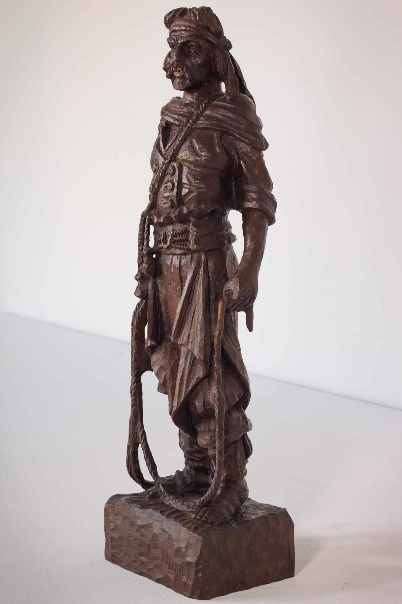 A wooden statue of a man with a cane and a hat.