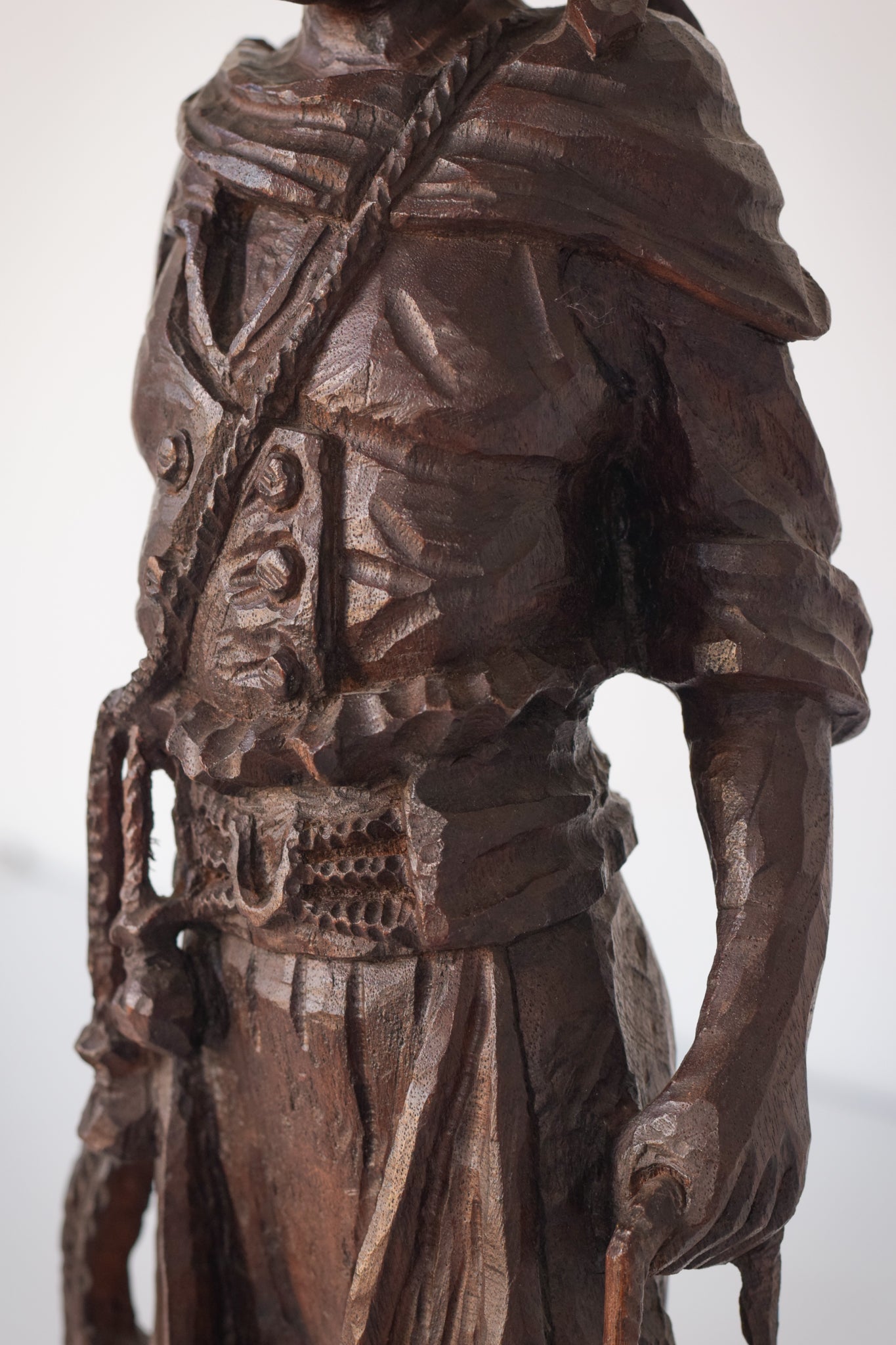 A wooden statue of a man with a cane and a hat.