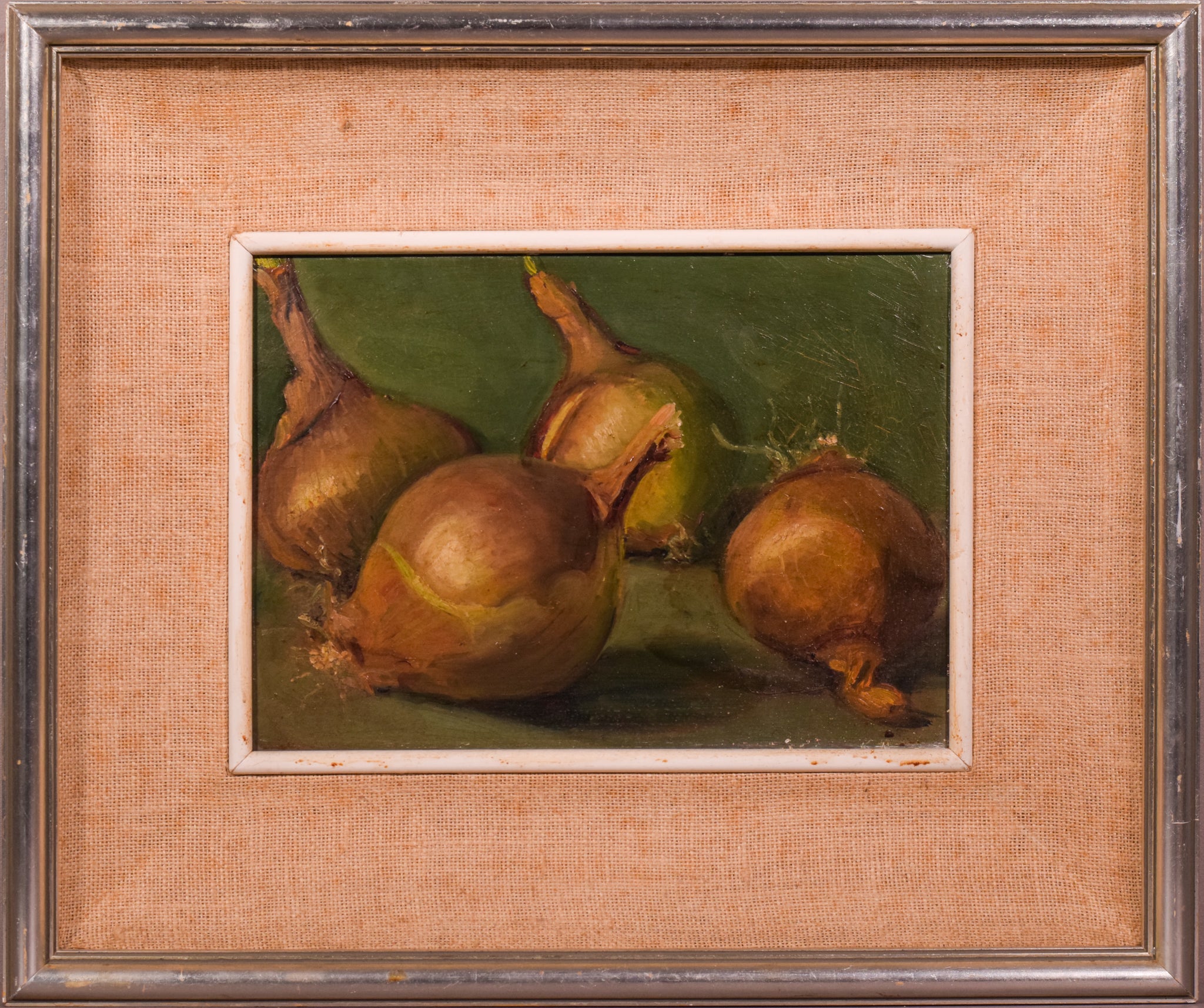A painting of three onions on a green surface.