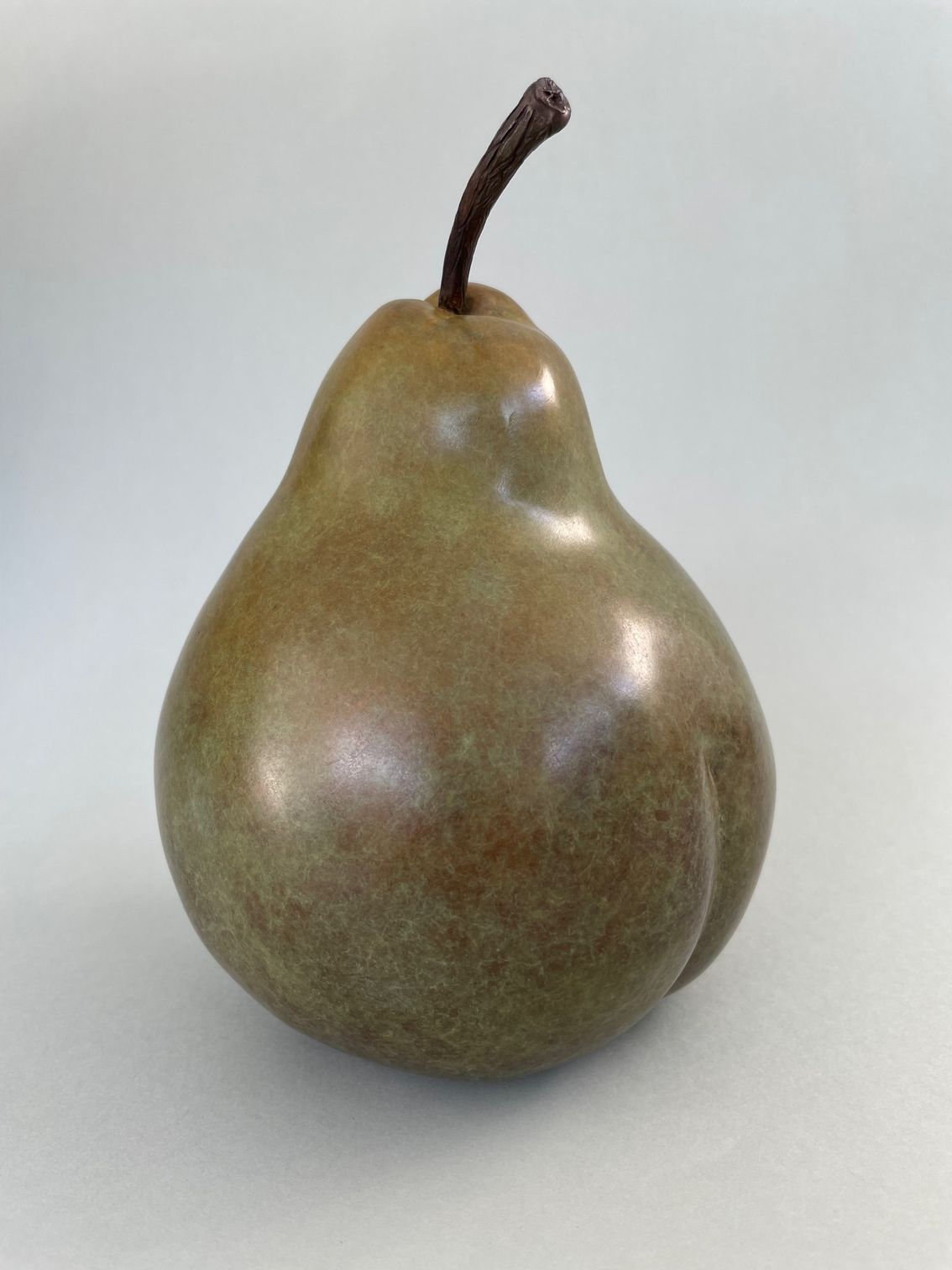 A realistic sculpture of a pear with a glossy, textured surface.
