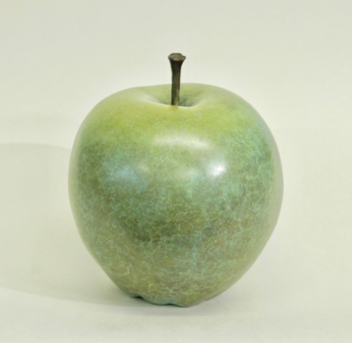 A green apple sitting on top of a white surface.