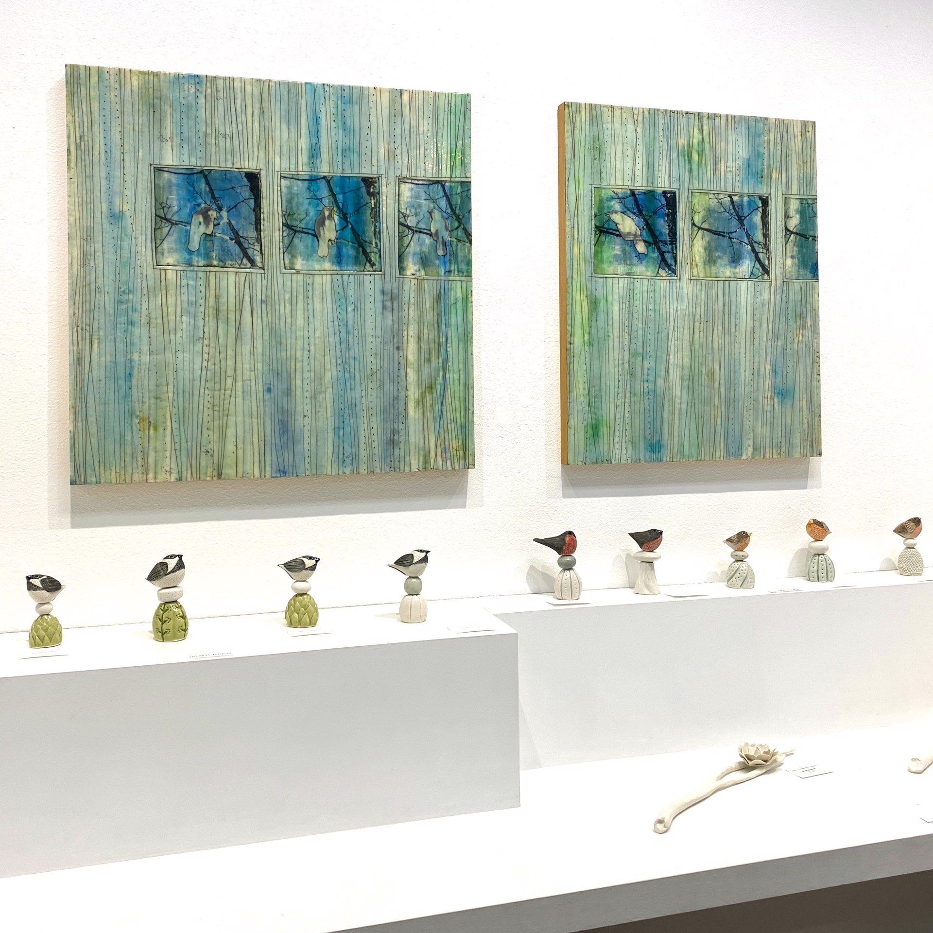 A mixed-media artwork featuring three framed birds perched on branches against a textured, vertical-lined background.