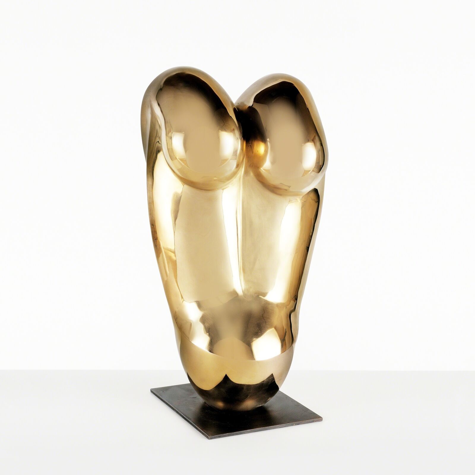 A gold sculpture on a metal stand on a white surface.
