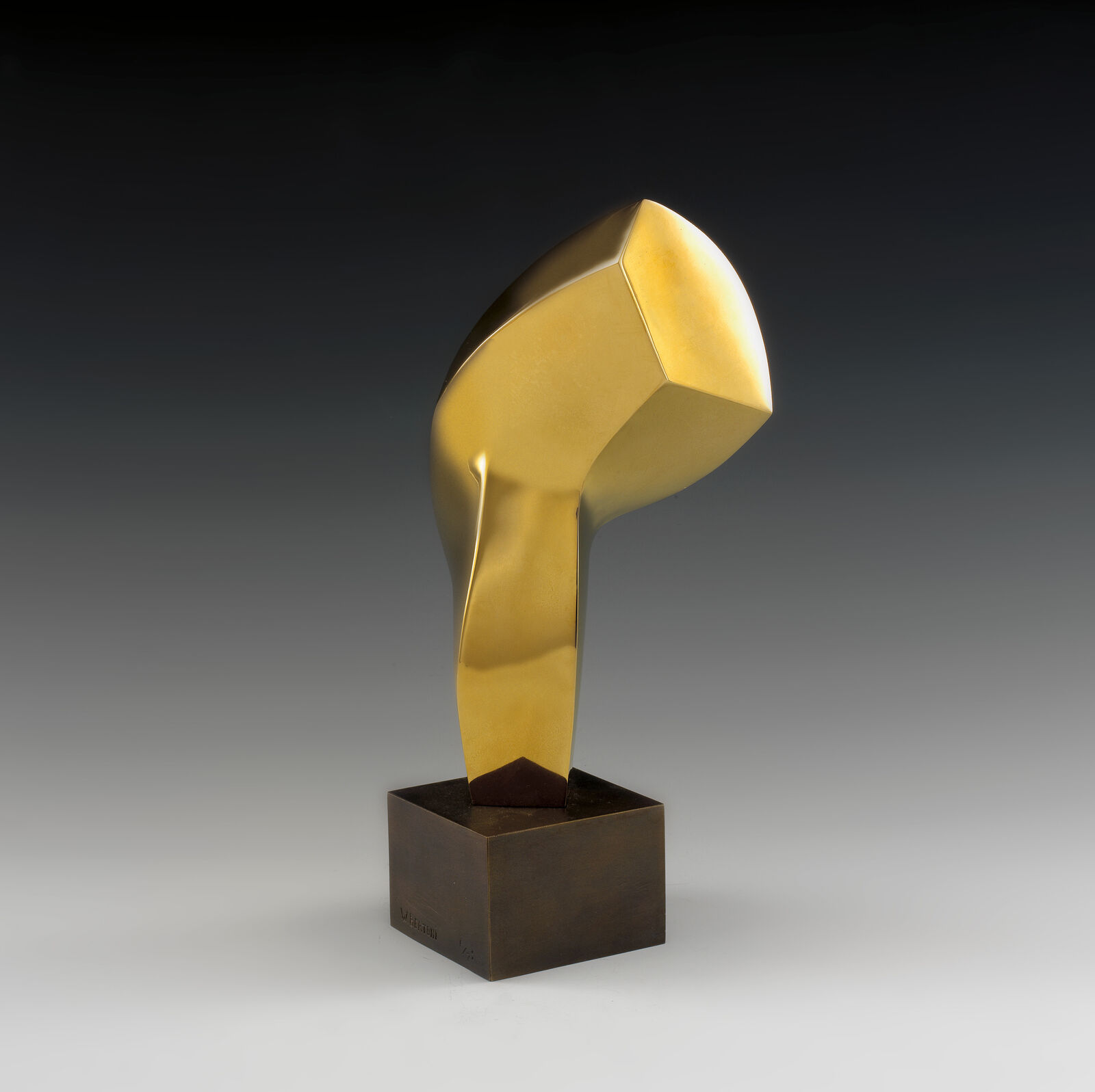 A gold sculpture on a wooden base on a gray background.