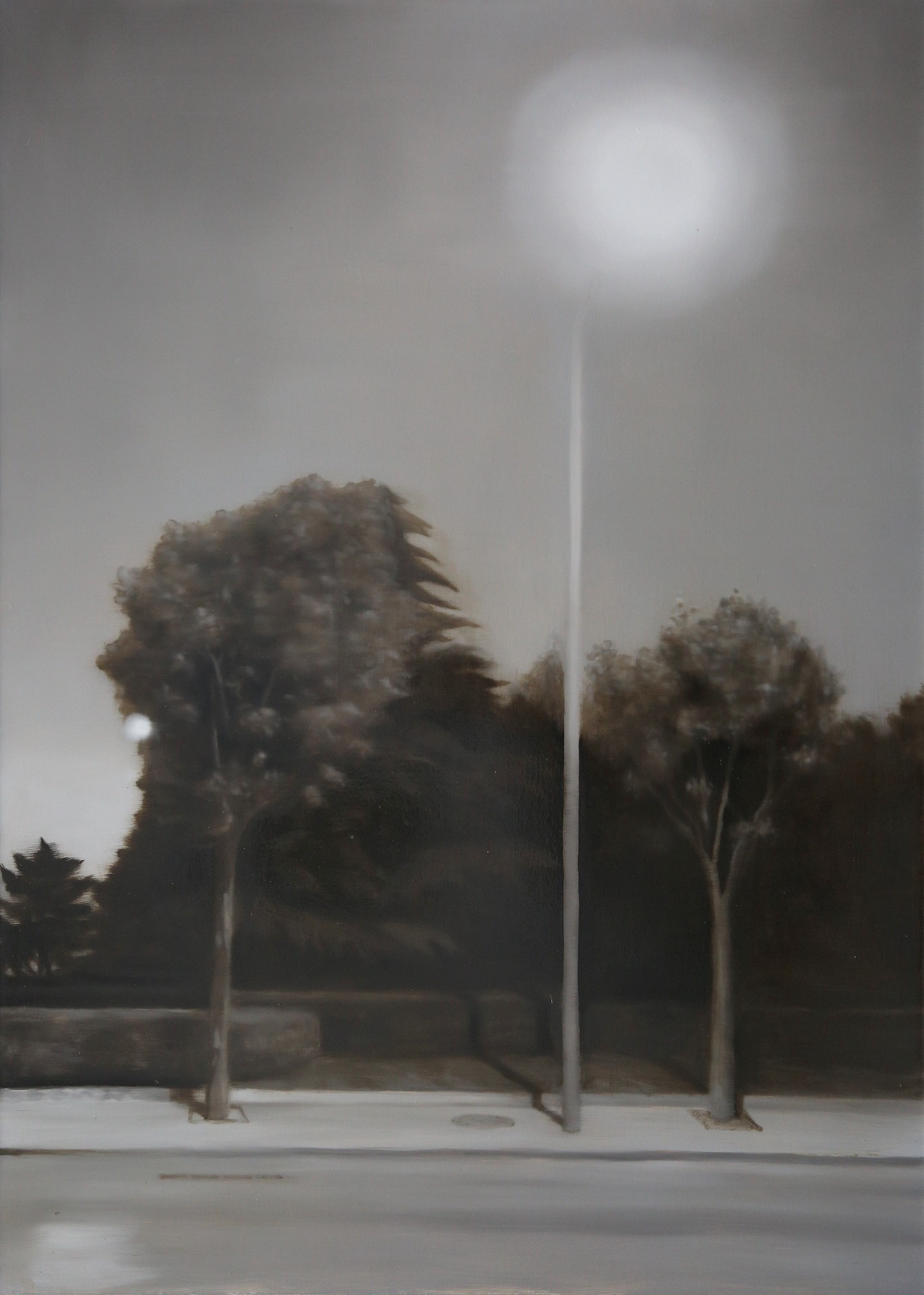 A moody street scene featuring a tall lamppost and trees under an overcast sky.