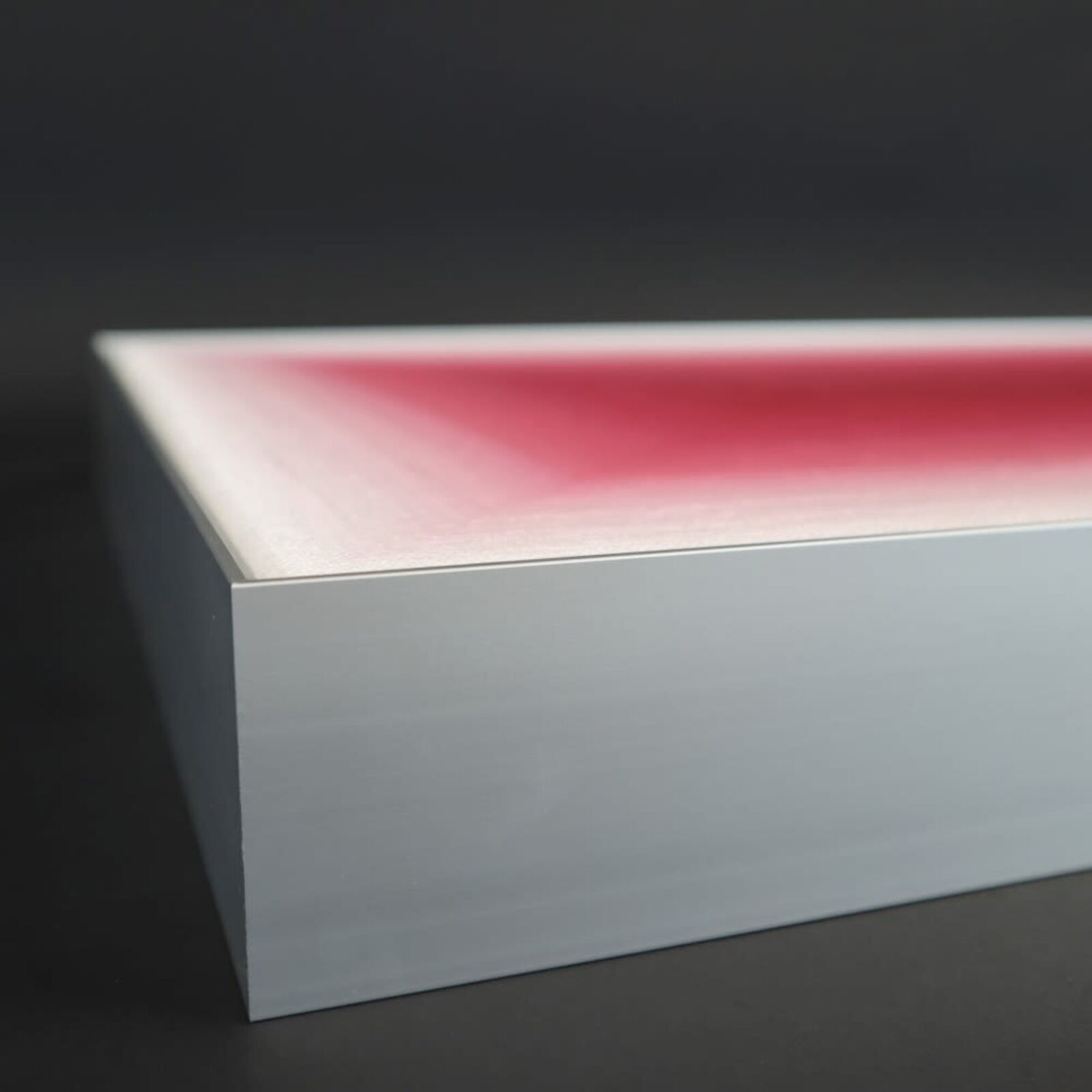 A pink room with a vase and a picture on the wall.