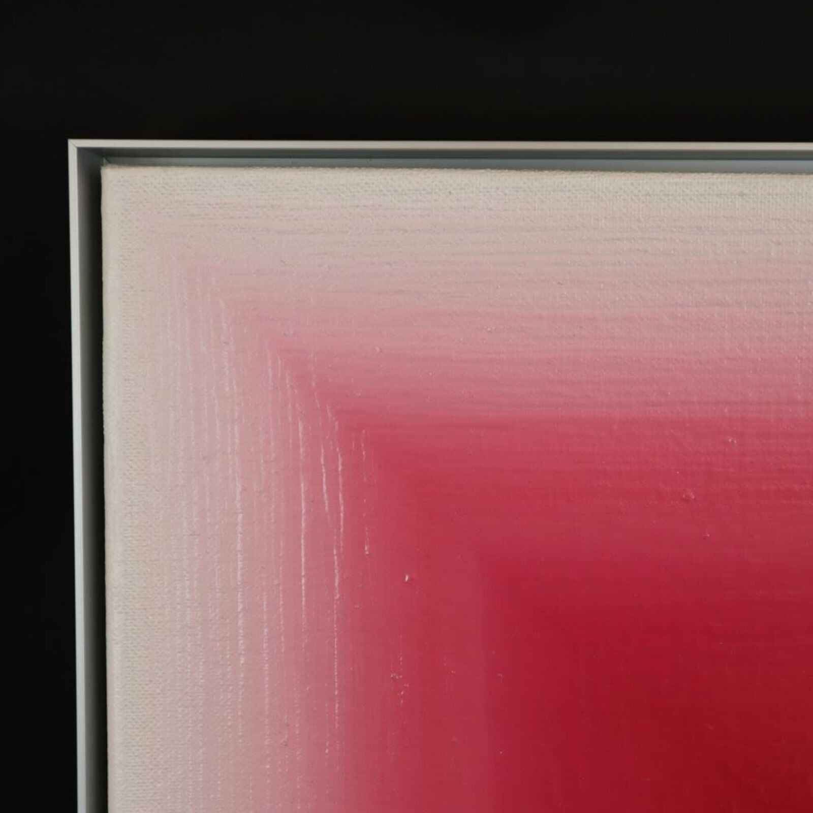 A pink room with a vase and a picture on the wall.