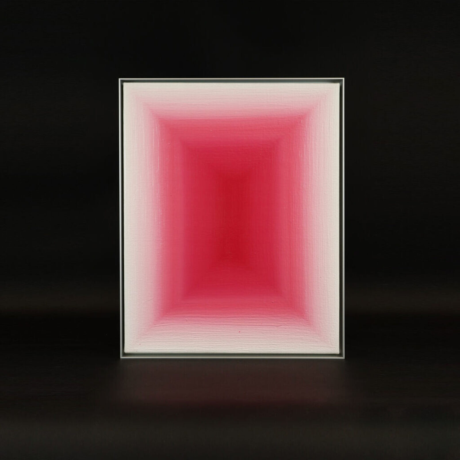 A framed abstract painting featuring a rectangular gradient of pink against a black background.