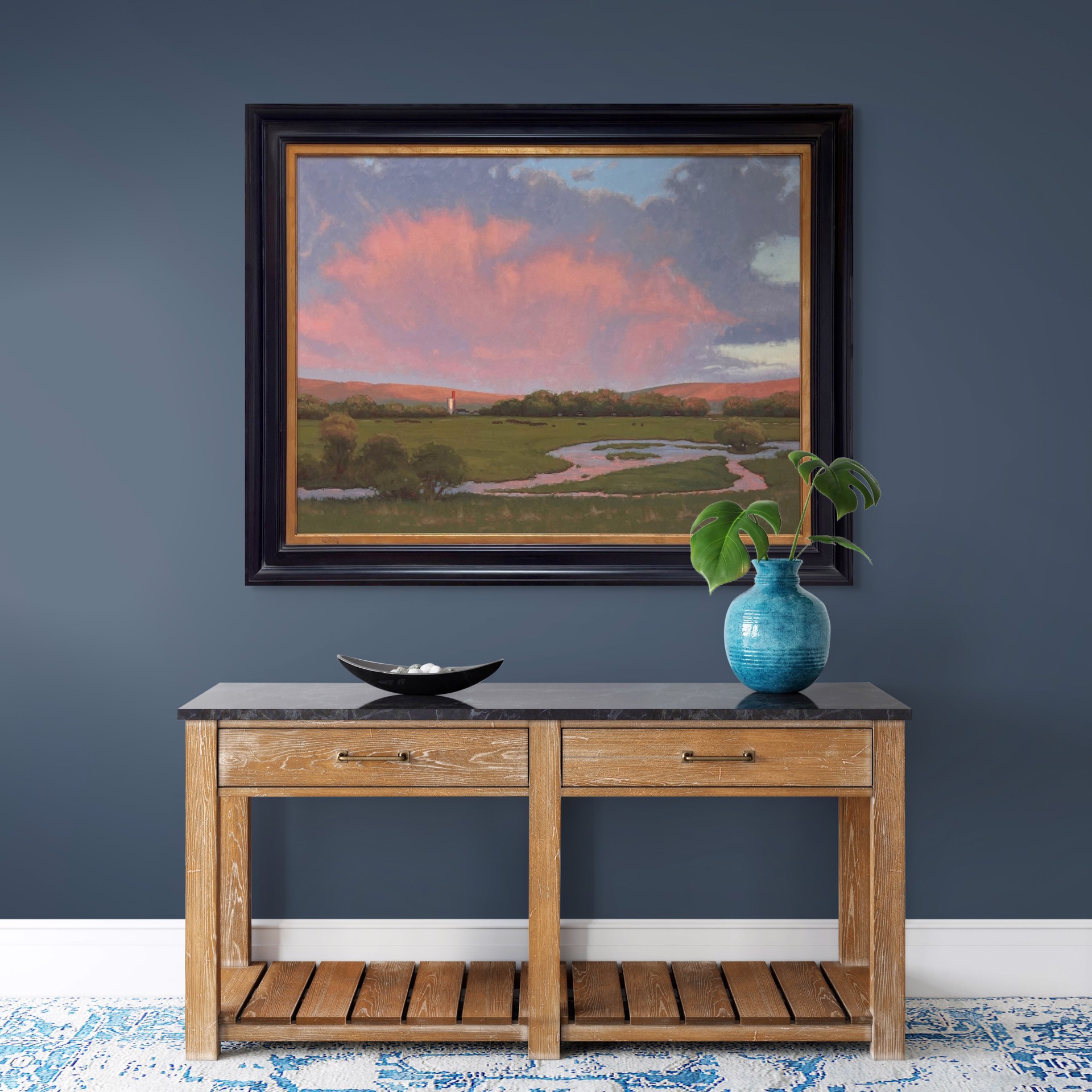 A serene landscape painting featuring a winding stream, green meadow, and dramatic pink clouds over distant hills.