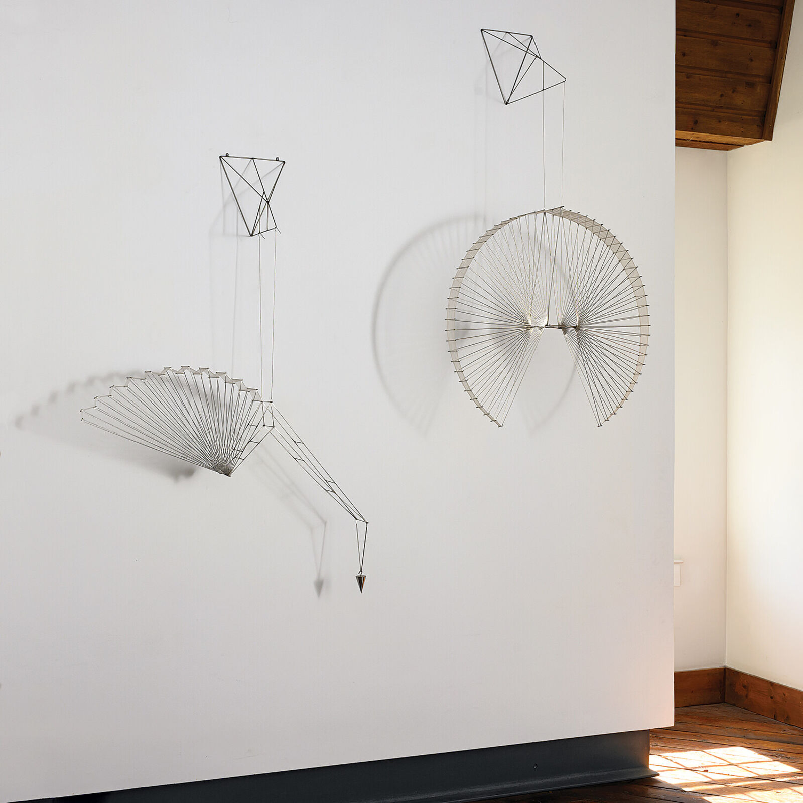 A metal sculpture of a bird hanging from a string.