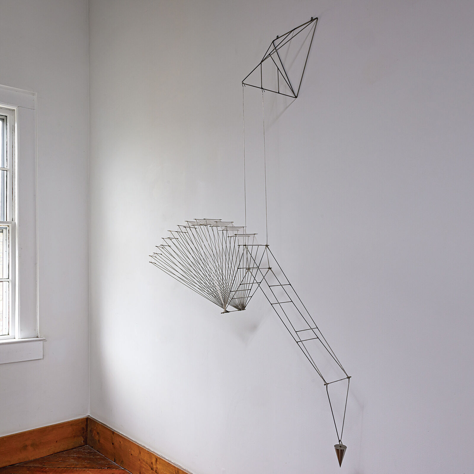 A metal sculpture of a bird hanging from a string.