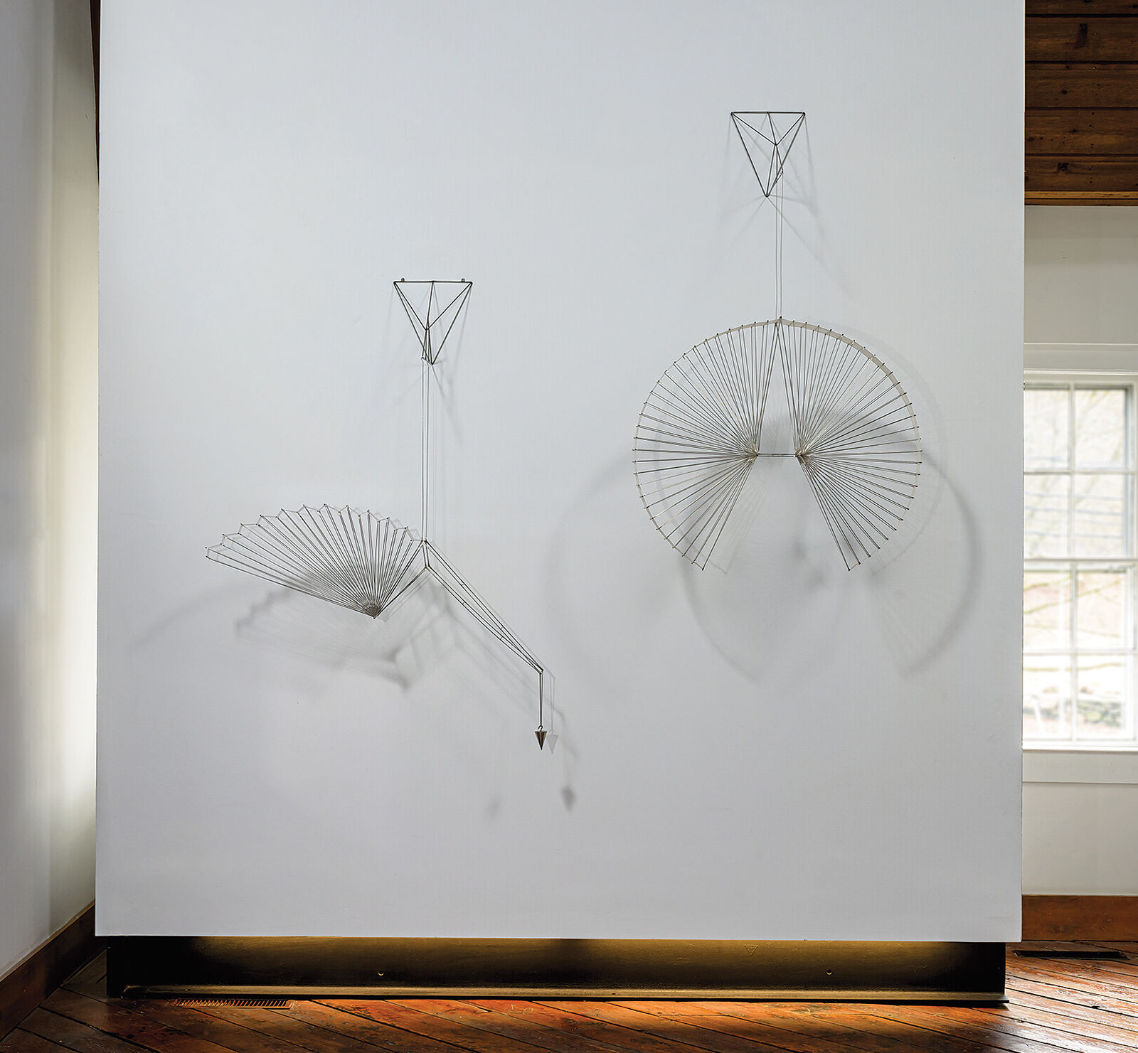 A metal sculpture of a bird hanging from a string.