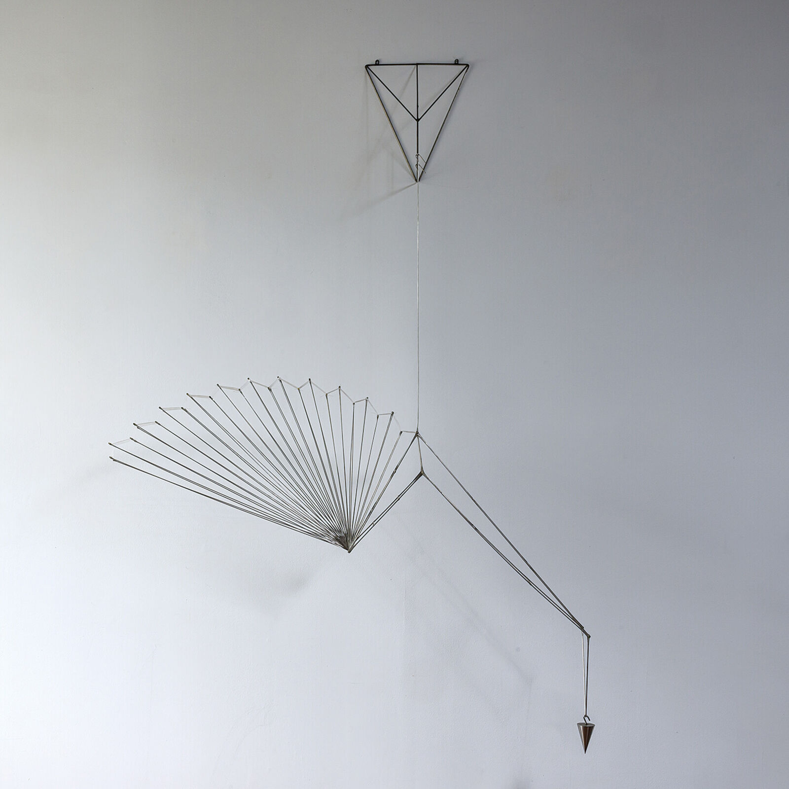 A metal sculpture of a bird hanging from a string.
