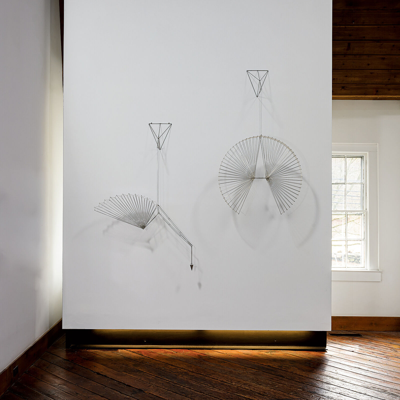 A metal sculpture of a bird hanging from a string.