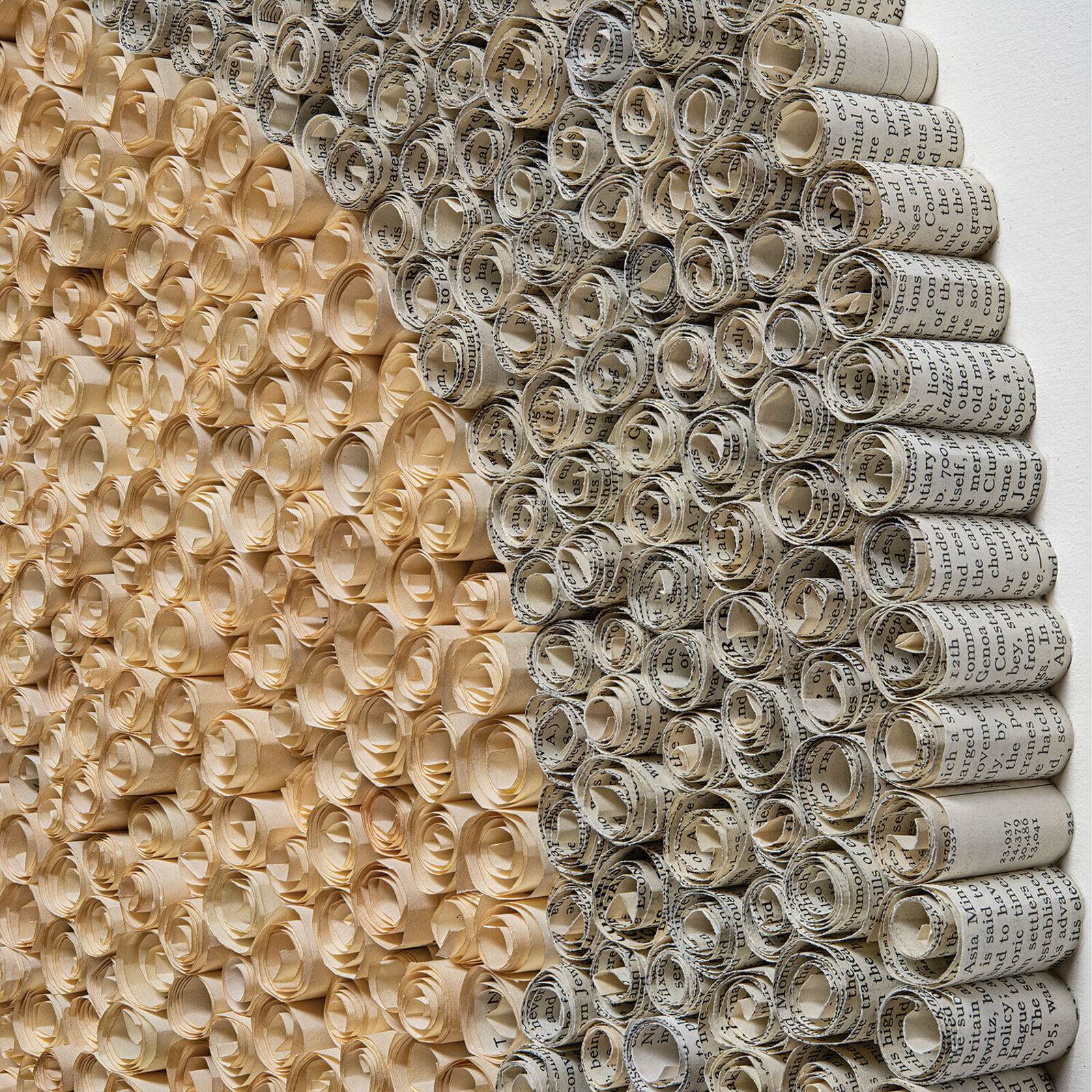 A textured circular artwork made of thousands of tiny rolled elements arranged in concentric rings.