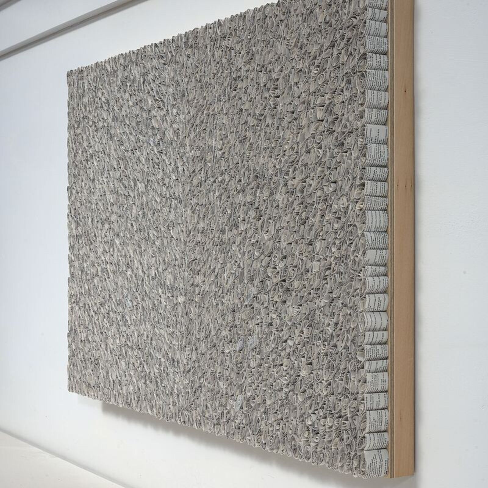 A black and white painting hanging on a wall next to a window.