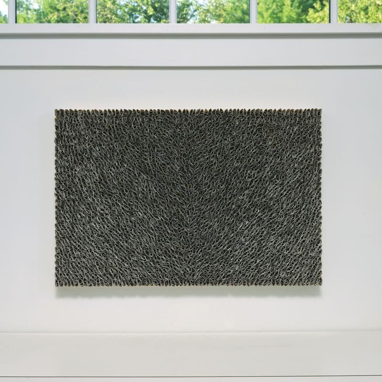 A black and white painting hanging on a wall next to a window.