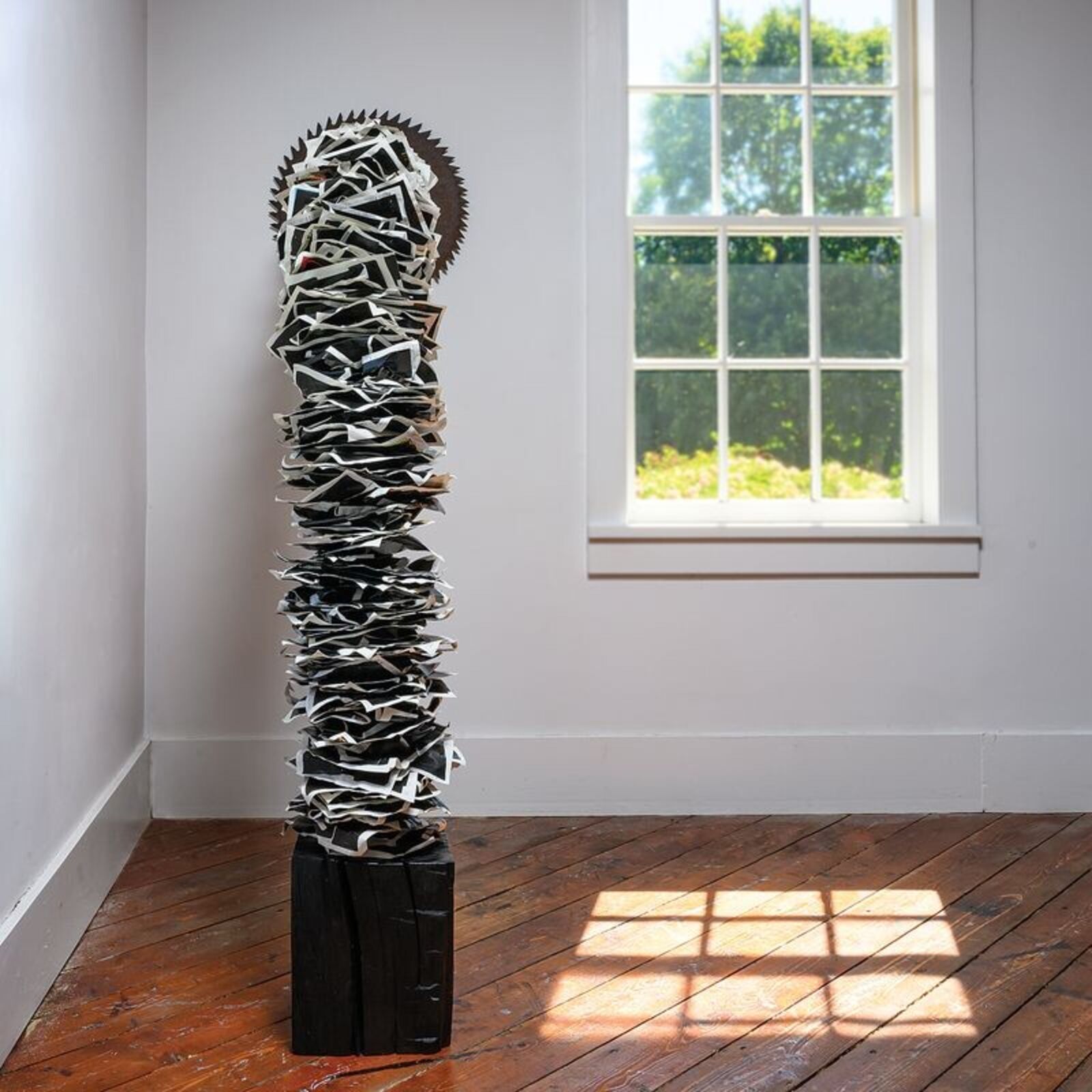 A sculptural installation featuring a jagged, metallic arch anchored by a dark block and ending in a spiked disc.